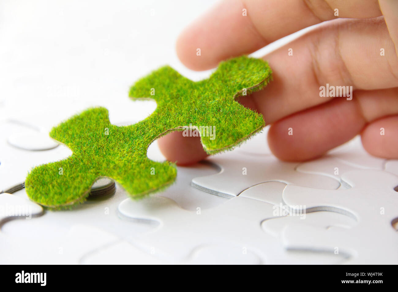 Main tenant une pièce de puzzle verte Banque D'Images