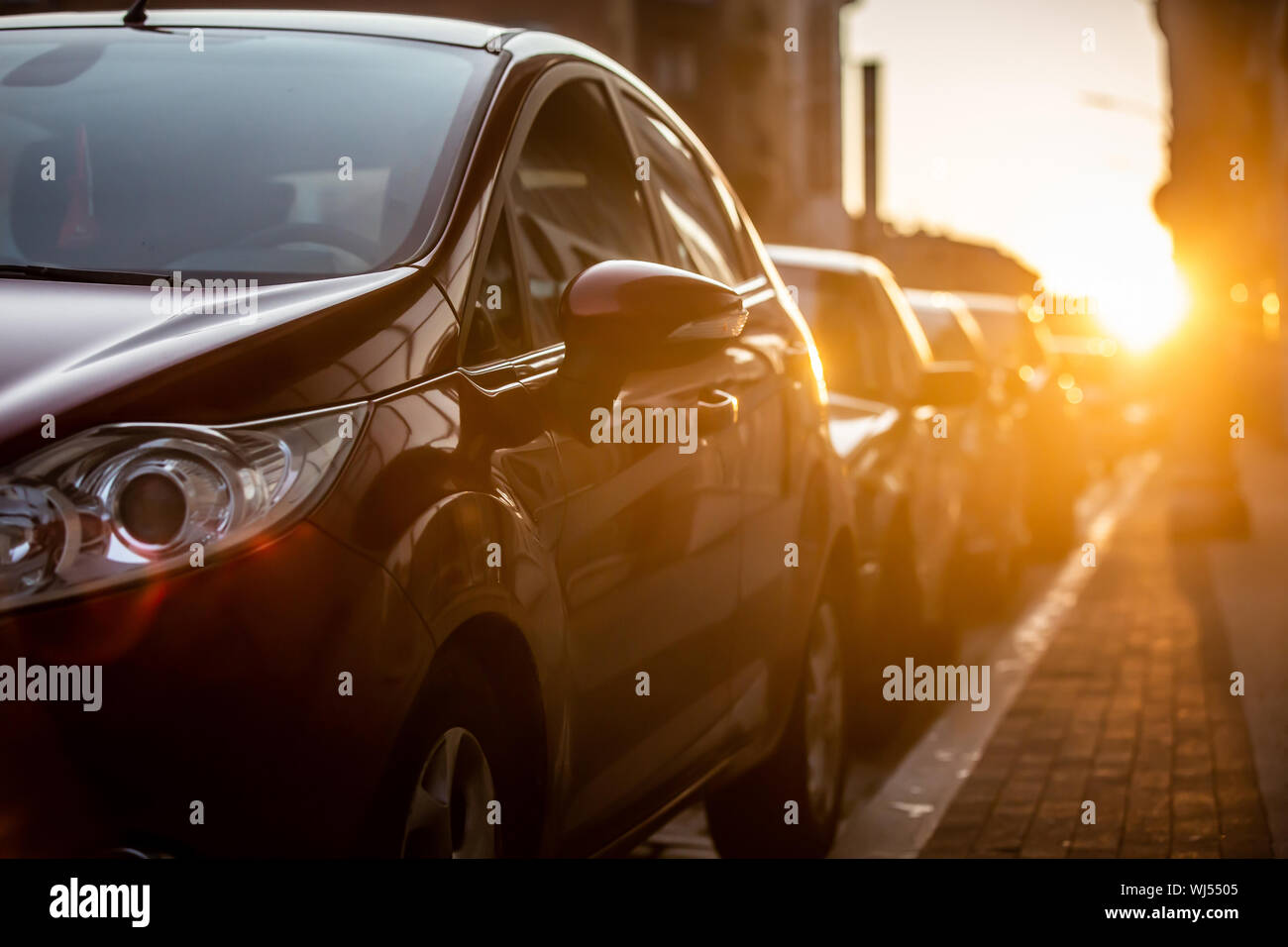 Voitures garées sur le côté de la route, avec fond coucher de soleil. Banque D'Images