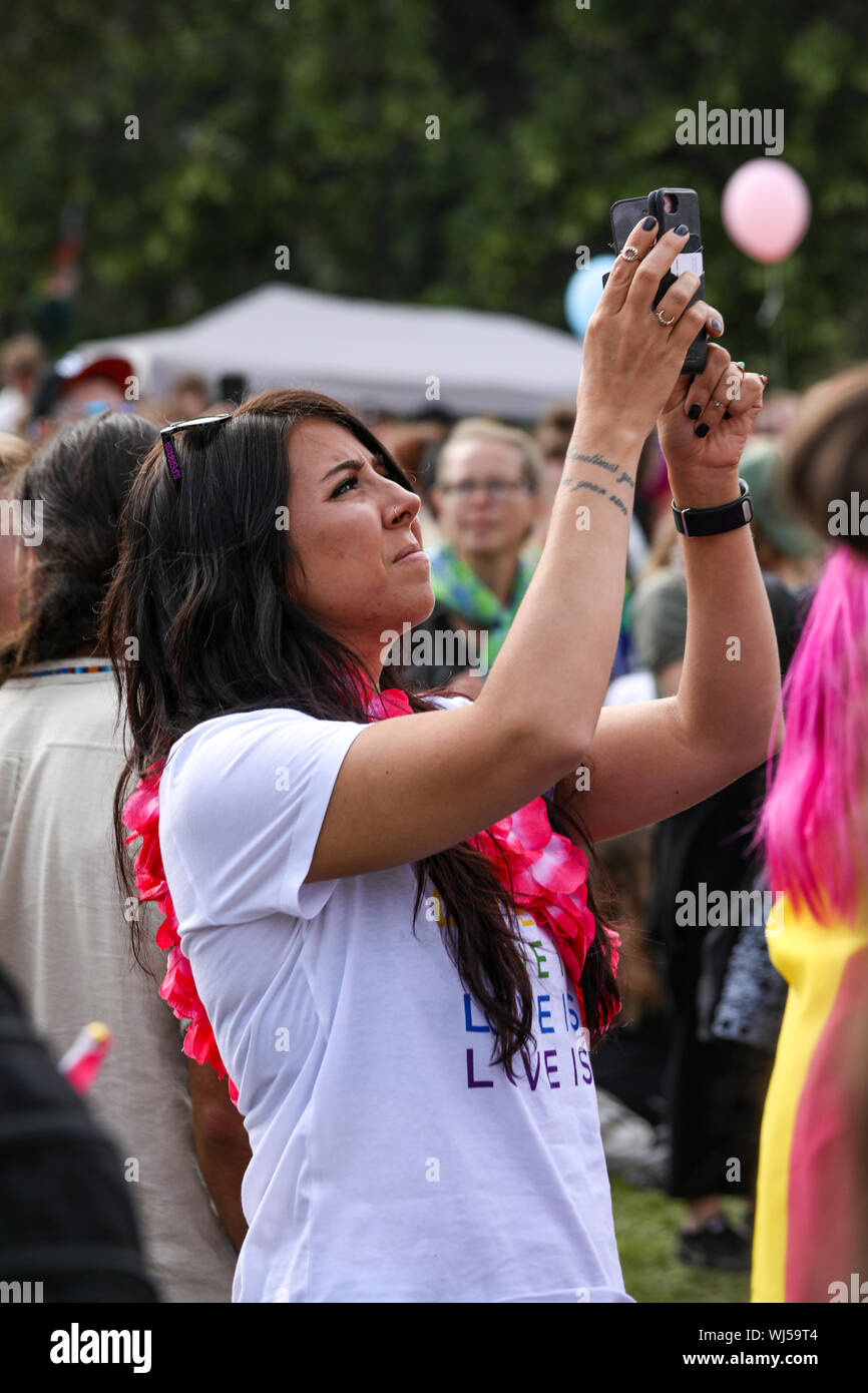 Jeune femme à prendre des photos avec un téléphone mobile à Helsinki Pride 2019 after-party dans le parc Kaivopuisto Banque D'Images