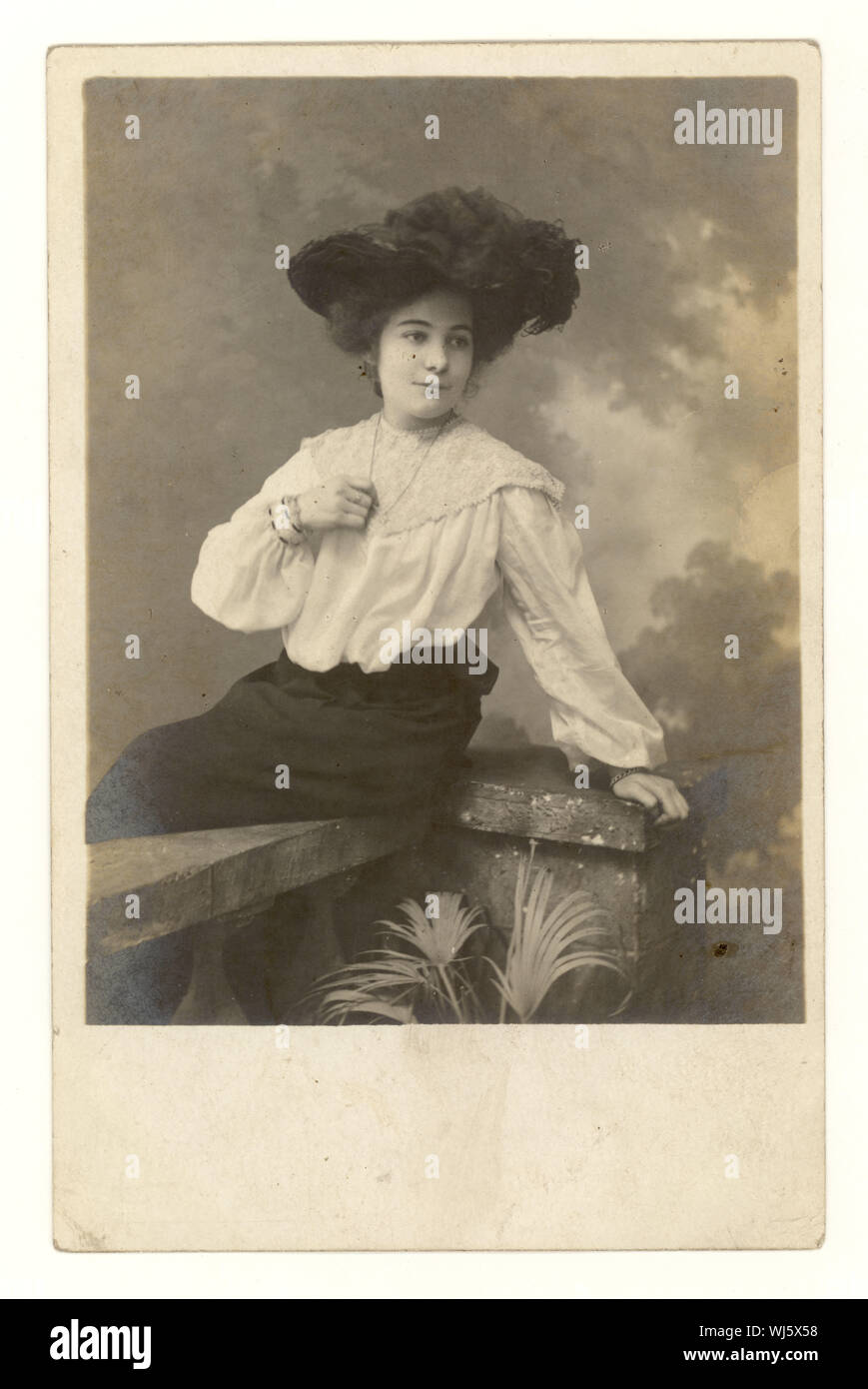 Au début des années 1900, la carte postale de portrait de studio de jolie jeune femme glamour portant un chapeau avec une plume en elle, blouse de dentelle, manches lâches, jupe vers 1904, Royaume-Uni Banque D'Images