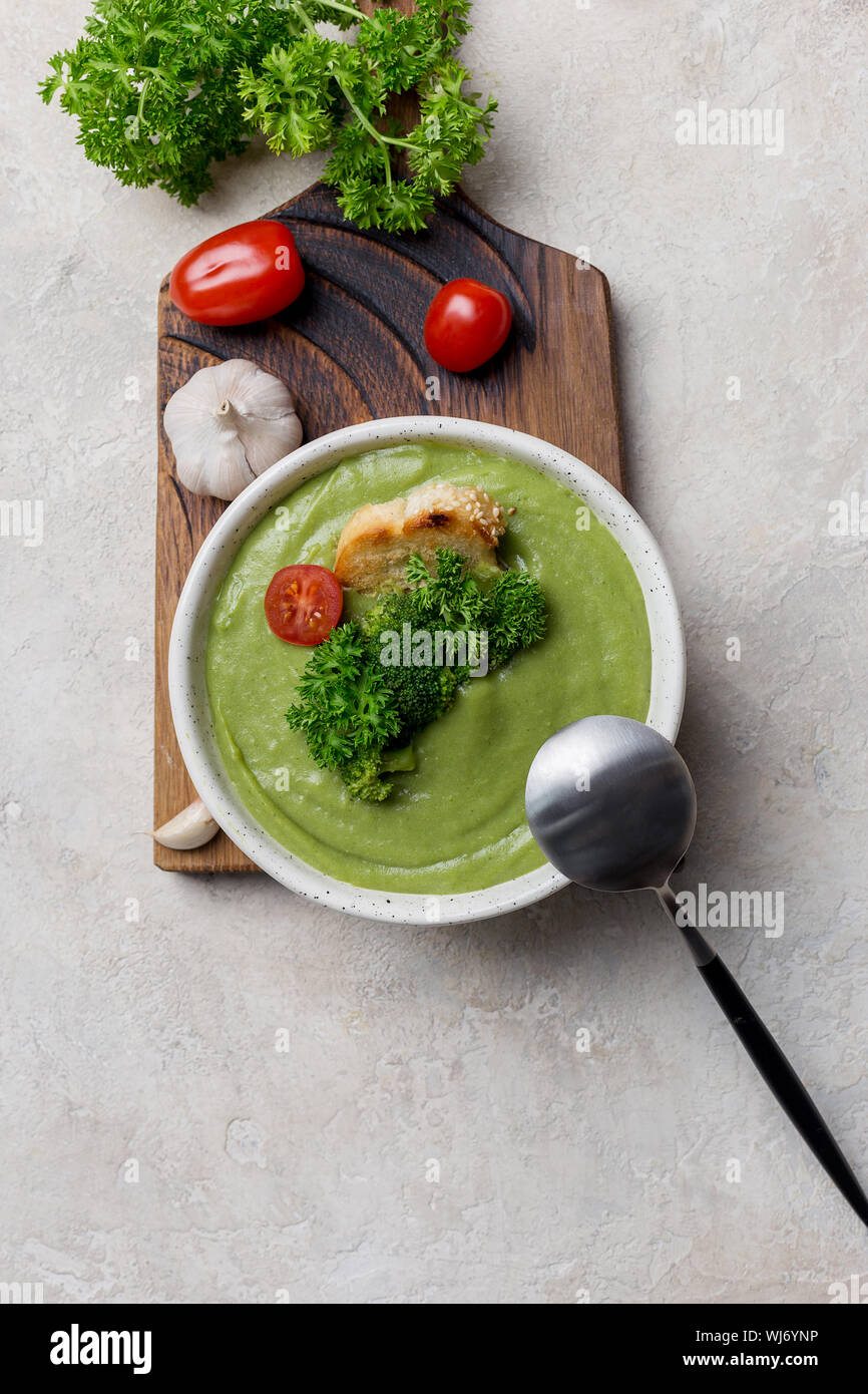Soupe crème de brocoli avec crouton et tomates cerises sur planche de bois Banque D'Images Soupe crème de brocoli avec crouton et tomates cerises sur planche de bois Banque D'Images
