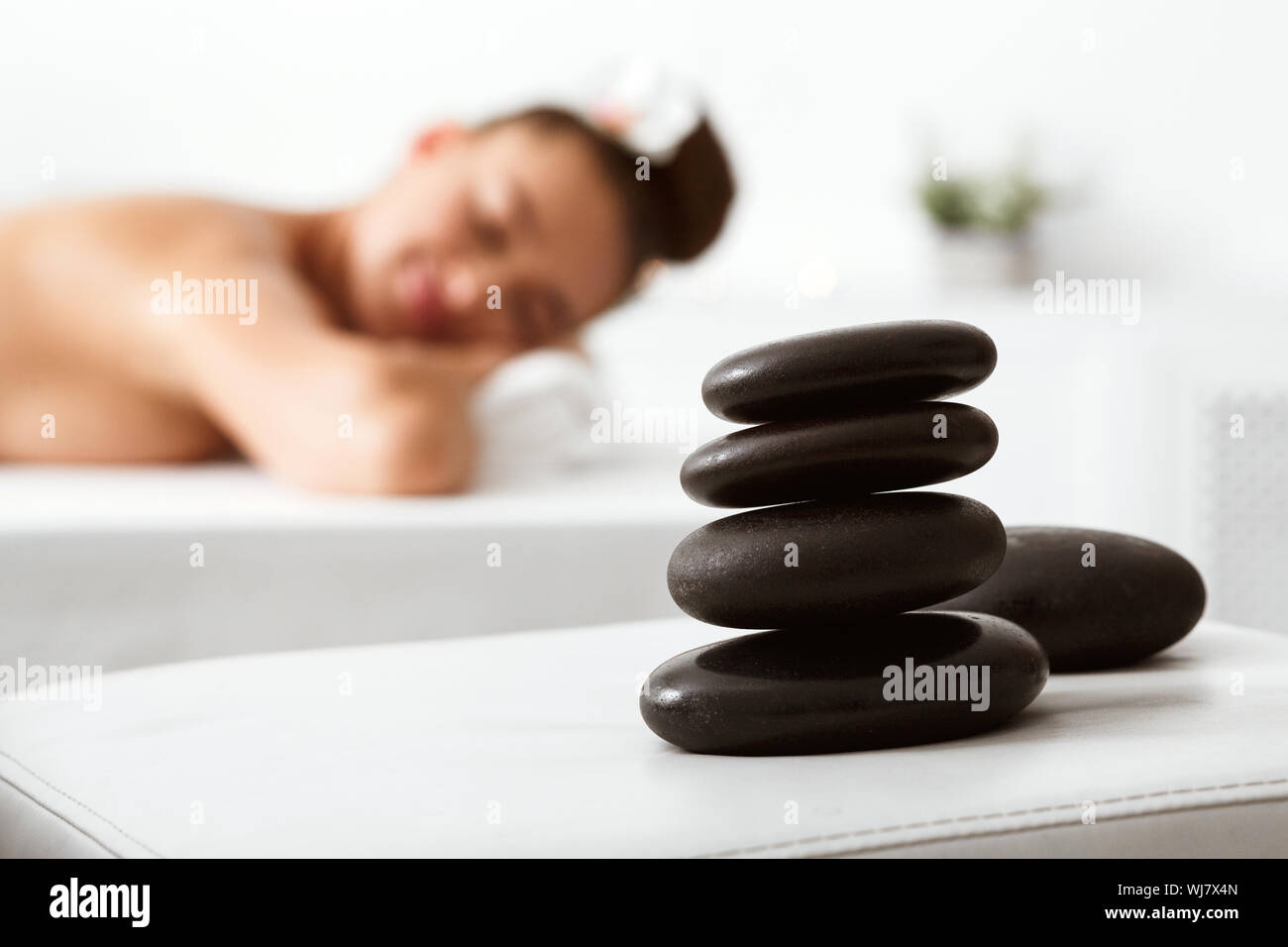 Pierres pour massages sur le premier plan, woman relaxing with closed eyes Banque D'Images