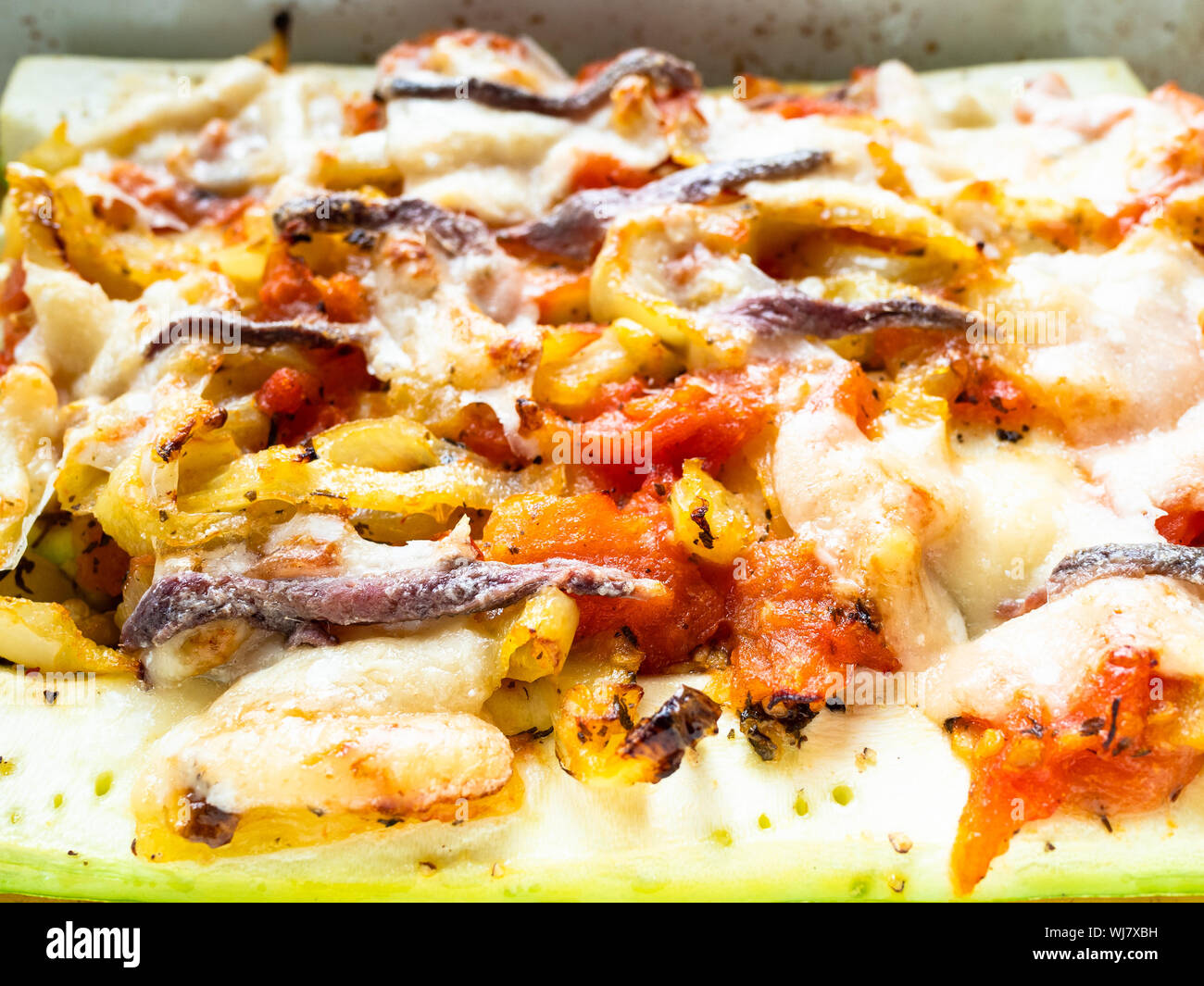Cuisine française - cuit au four avec des tranches de courgettes et poivrons tomates avec topping from cheece Parmesan, l'ail et les anchois avec la vinaigrette d'huile d'olive Banque D'Images