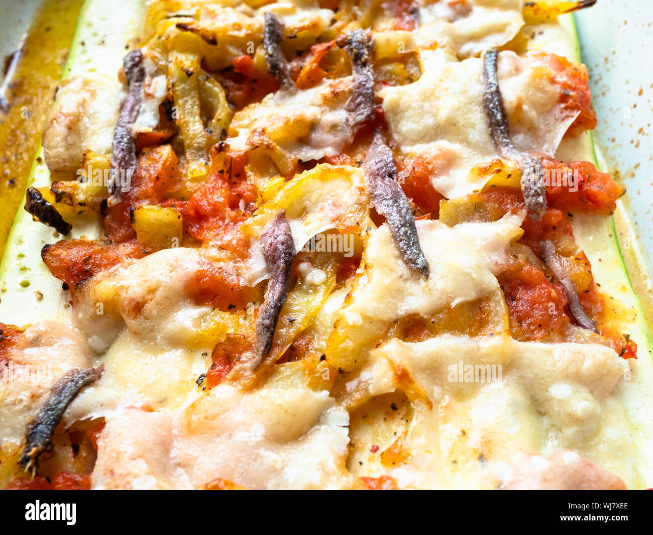 Cuisine française - courgette cuite au four avec des tranches de tomate et piment doux avec topping from cheece Parmesan, l'ail et les anchois avec la vinaigrette de ol Banque D'Images