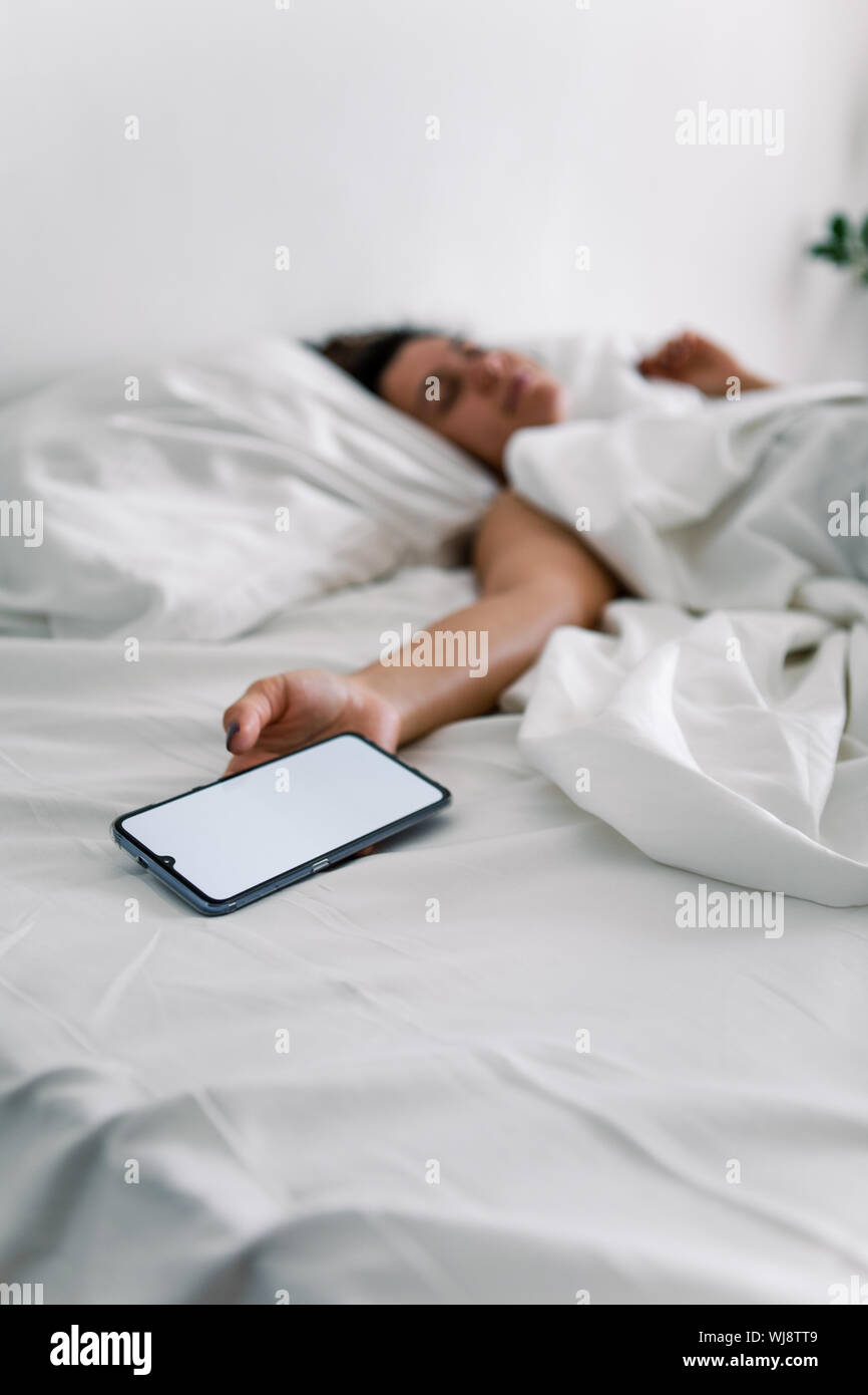 Woman sleeping in bed téléphone dans sa main libre smartphone floue fond  sur les gens Photo Stock - Alamy