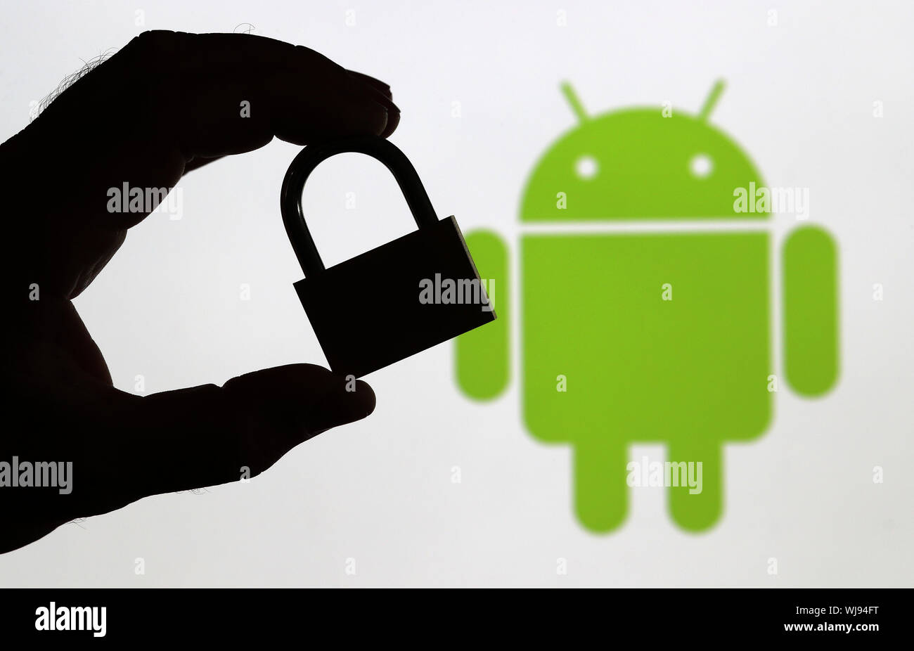 Un homme tenant un cadenas devant un écran d'ordinateur affichant le logo Android pour illustrer la sécurité des données (usage éditorial uniquement) Banque D'Images