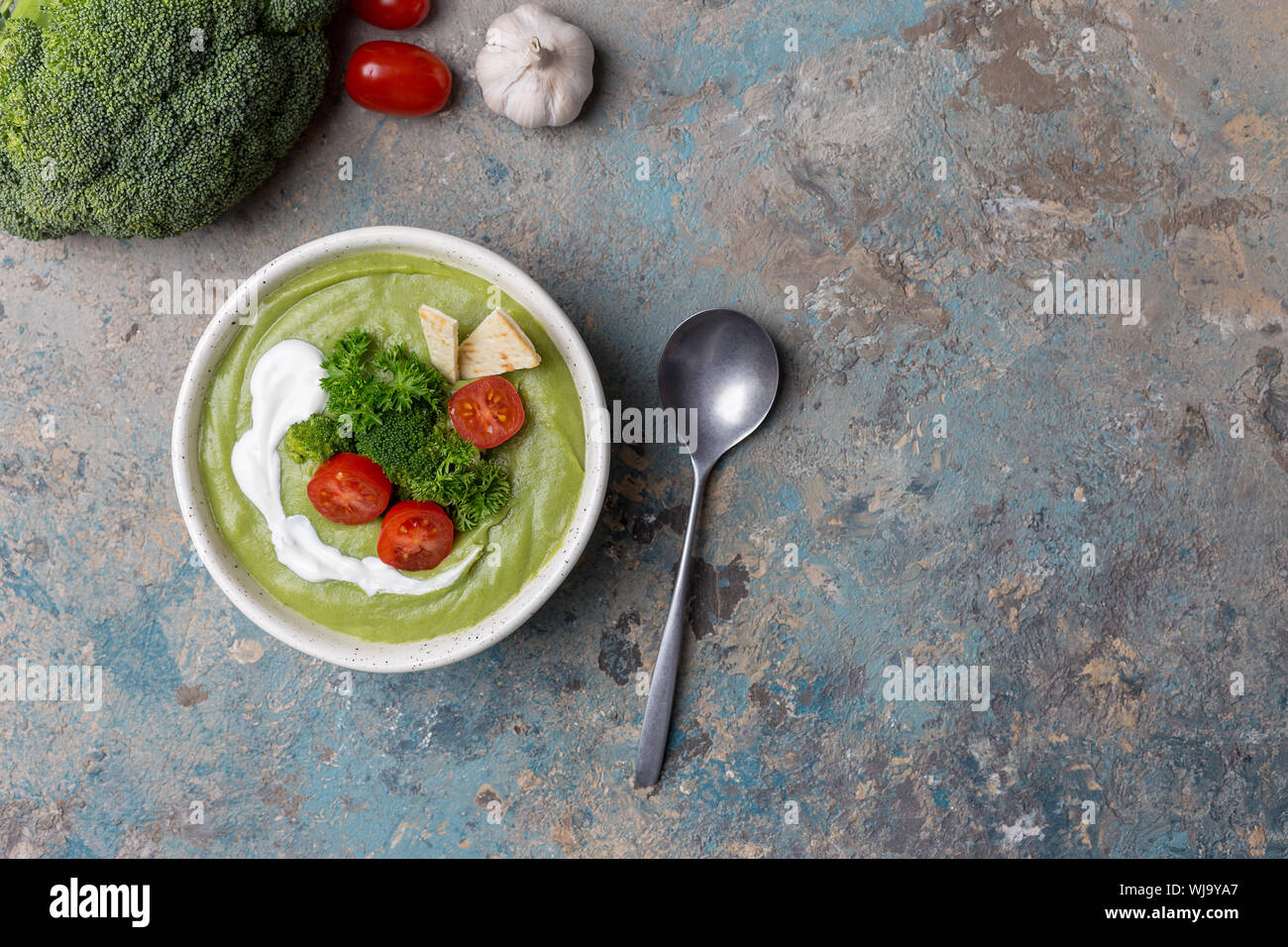 Crème de brocoli soupe avec des ingrédients crus, tomates cerises, le persil, le brocoli, l'ail mûr entier et une cuillère sur le béton. Concept de la cuisine de saison Banque D'Images Crème de brocoli soupe avec des ingrédients crus, tomates cerises, le persil, le brocoli, l'ail mûr entier et une cuillère sur le béton. Concept de la cuisine de saison Banque D'Images