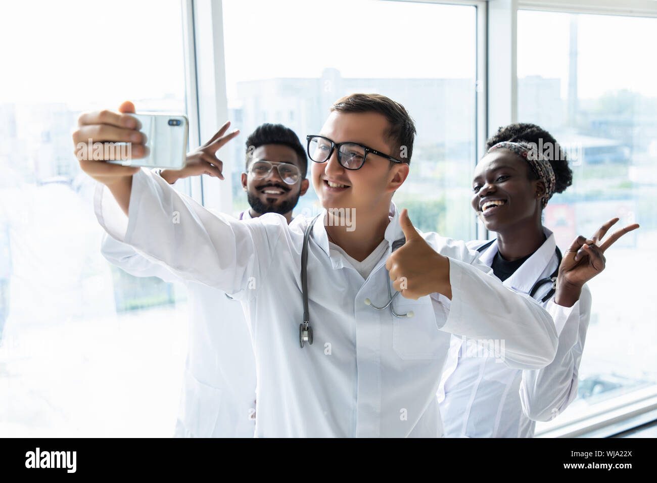 Groupe de médecins stagiaires en tenant vos autoportraits dans le hall de l'hôpital Banque D'Images