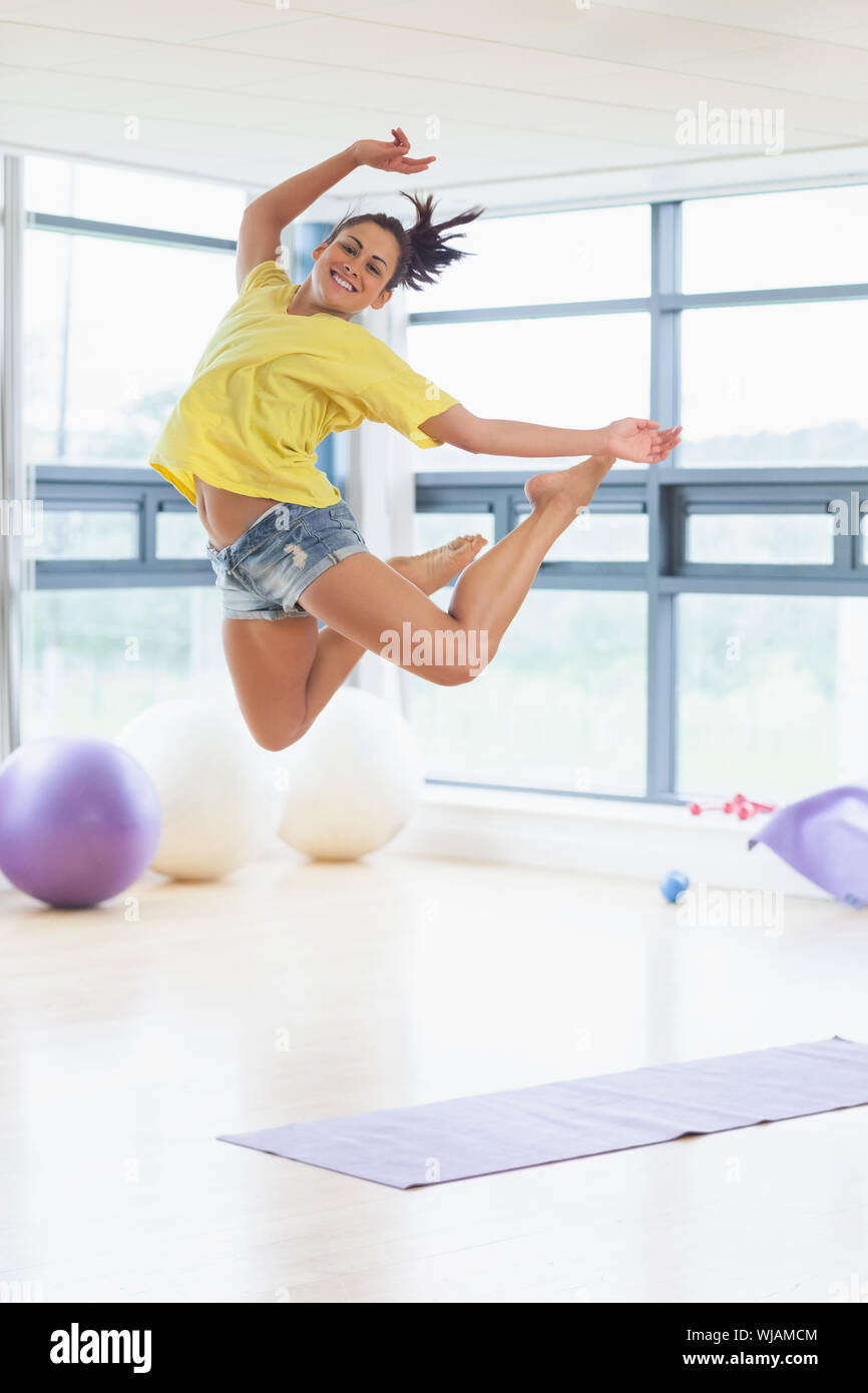 Young woman jumping in fitness studio Banque D'Images