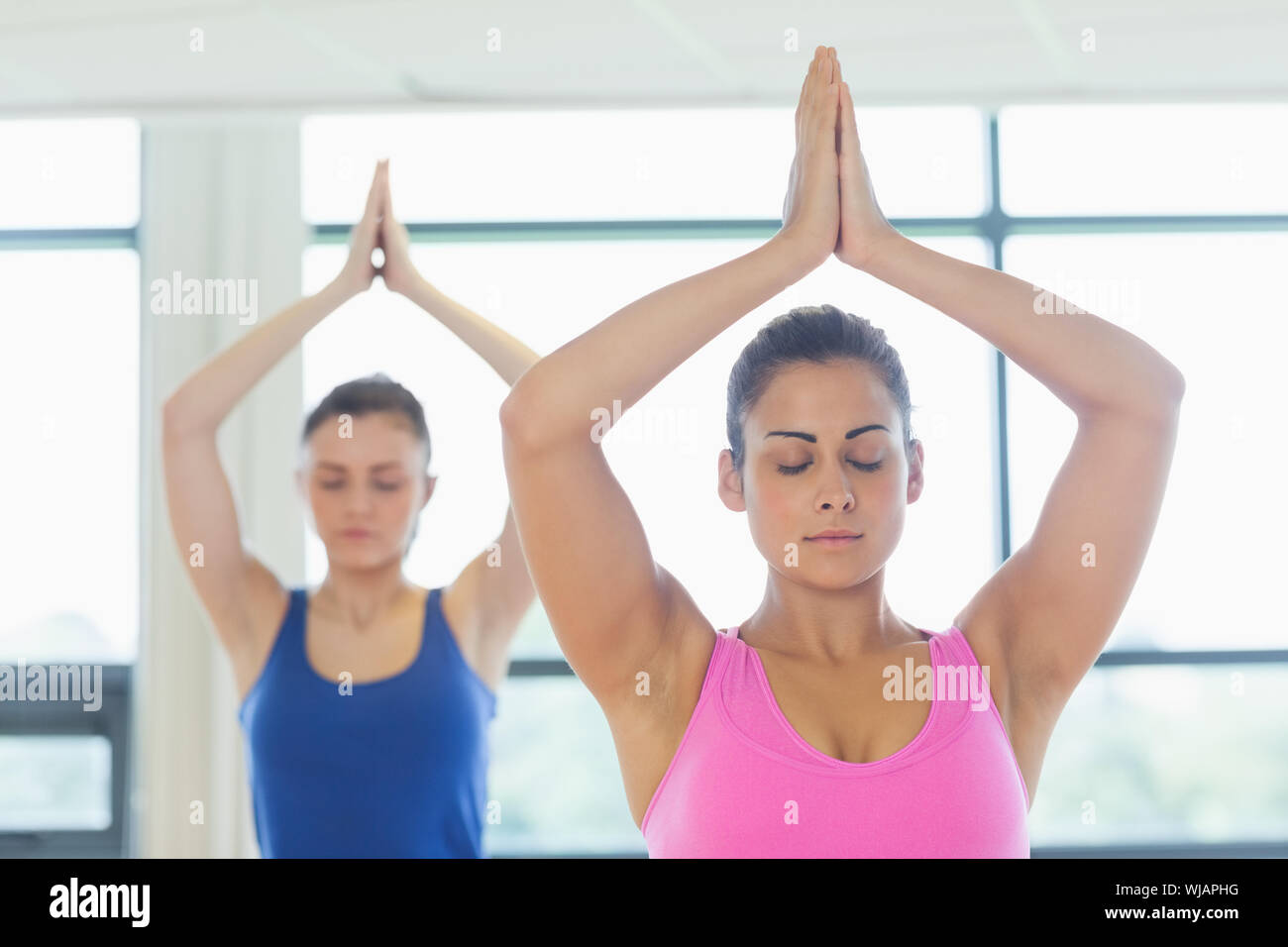 Deux femmes en position Namaste with eyes closed at fitness studio Banque D'Images