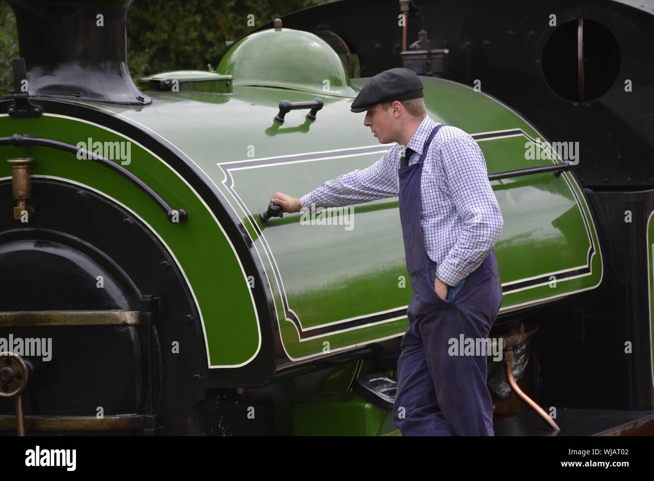 Un moteur conducteur en costume victorien période inspecte sa locomotive à vapeur d'un fer préservé dans le Northamptonshire, UK Banque D'Images