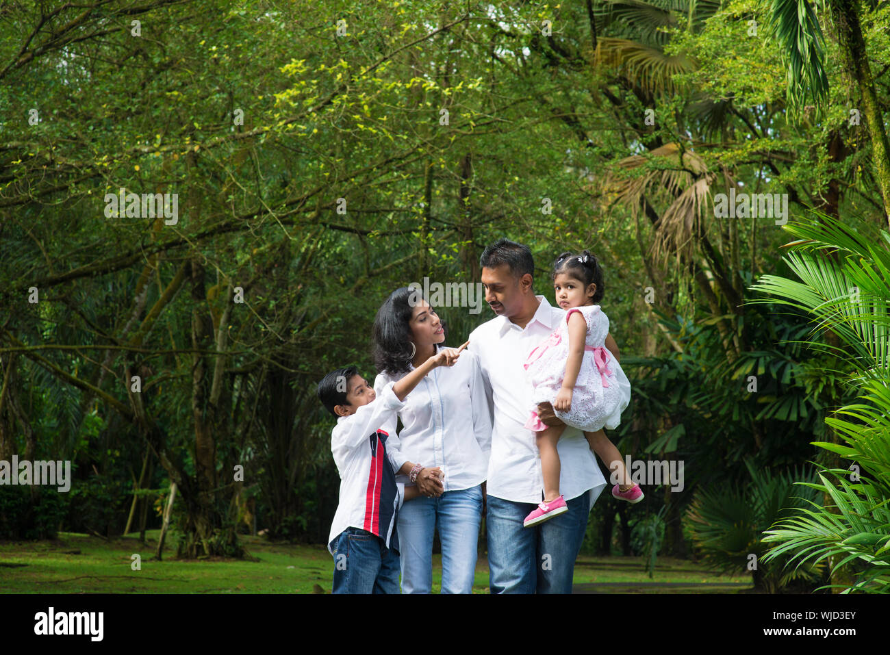 Famille indienne à l'extérieur. Les parents et les enfants marcher sur chemin de jardin. Explorer la nature, le mode de vie de loisirs. Banque D'Images