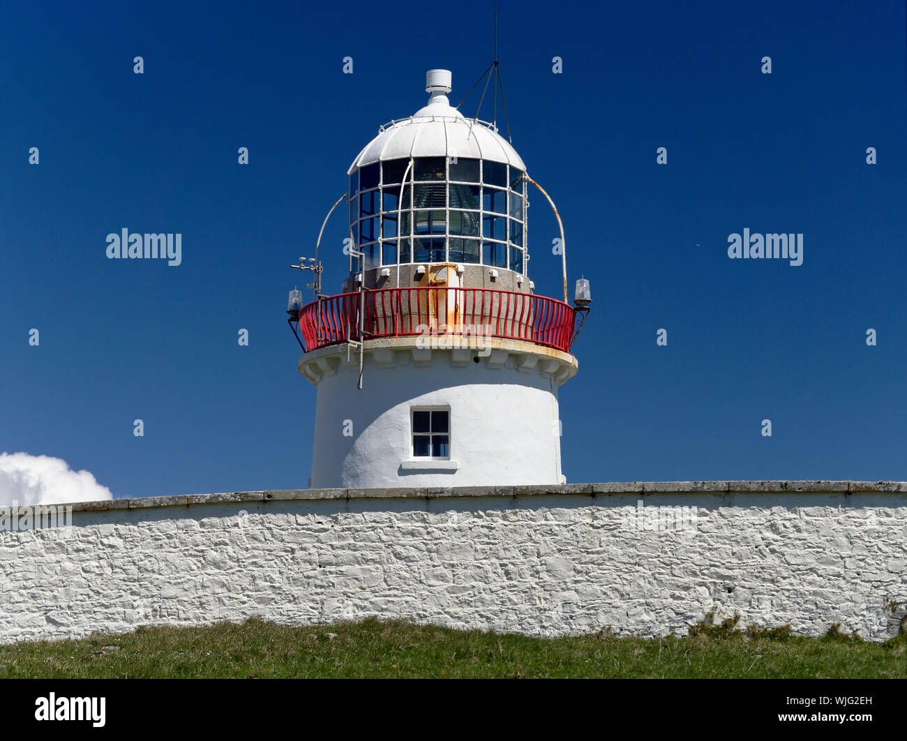 St John's Point, dans le comté de Donegal, Irlande - Mai 21st, 2019 - phare blanc blanc derrière le mur en pierre en face d'un ciel bleu clair Banque D'Images