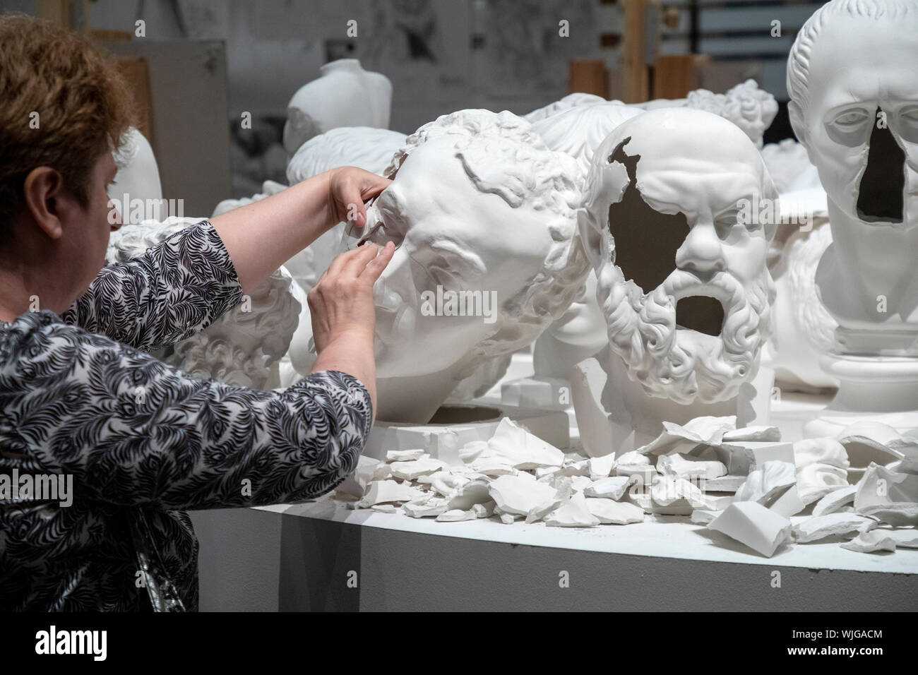 Une femme essaie de monter un buste en plâtre à une exposition d'art  contemporain 'Atlas des studios de création de Moscou' dans la zone  'Manege' Hall à Moscou, RU Photo Stock -