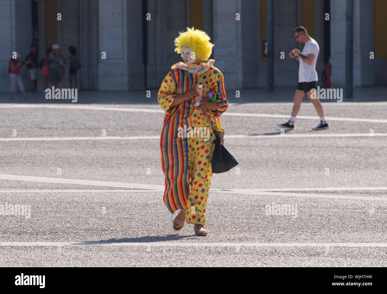 Pas de service d'un clown rue prenant quelques temps à Lisbonne, sur la Praça do Comércio Banque D'Images