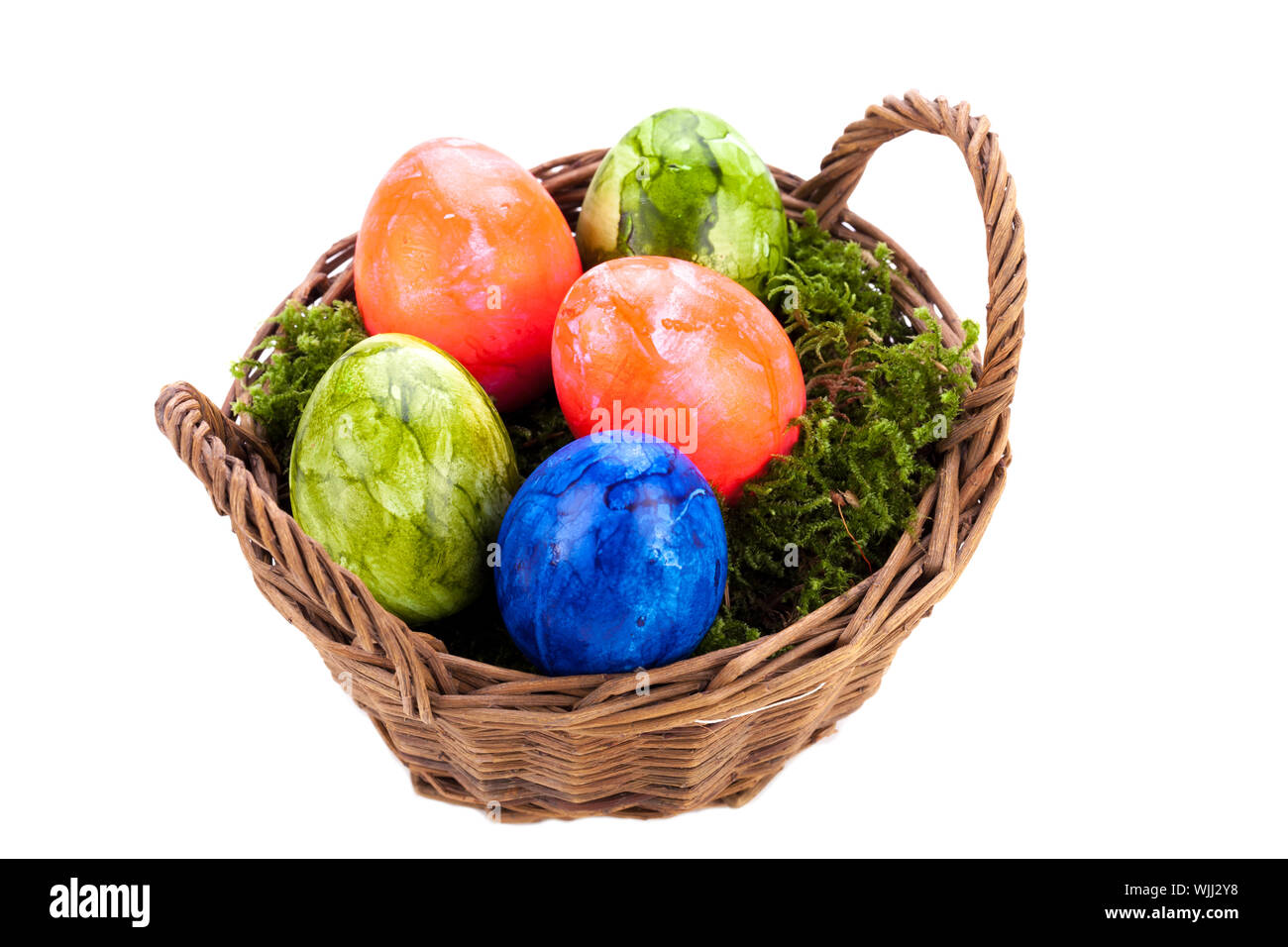 Panier en osier rustique aux couleurs vives des traditionnels peints à la main les oeufs de Pâques avec un motif marbré blotti dans un lit de mousse verte, high angle view Banque D'Images