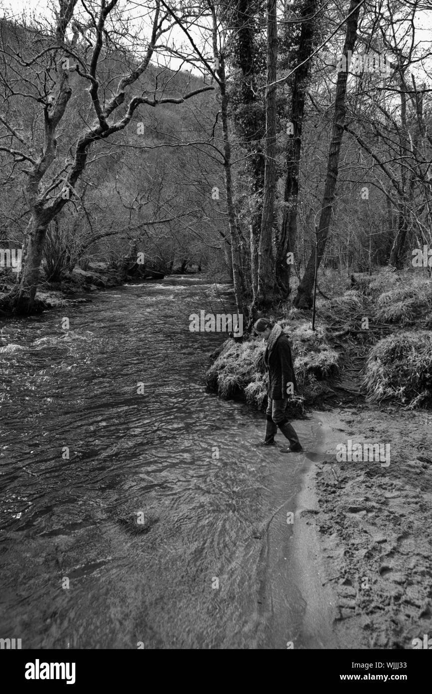 Jeune femme patauge dans l'eau : La rivière Teign, près d'un escalier pont, Devon, UK. Version noir et blanc. Parution du modèle Banque D'Images