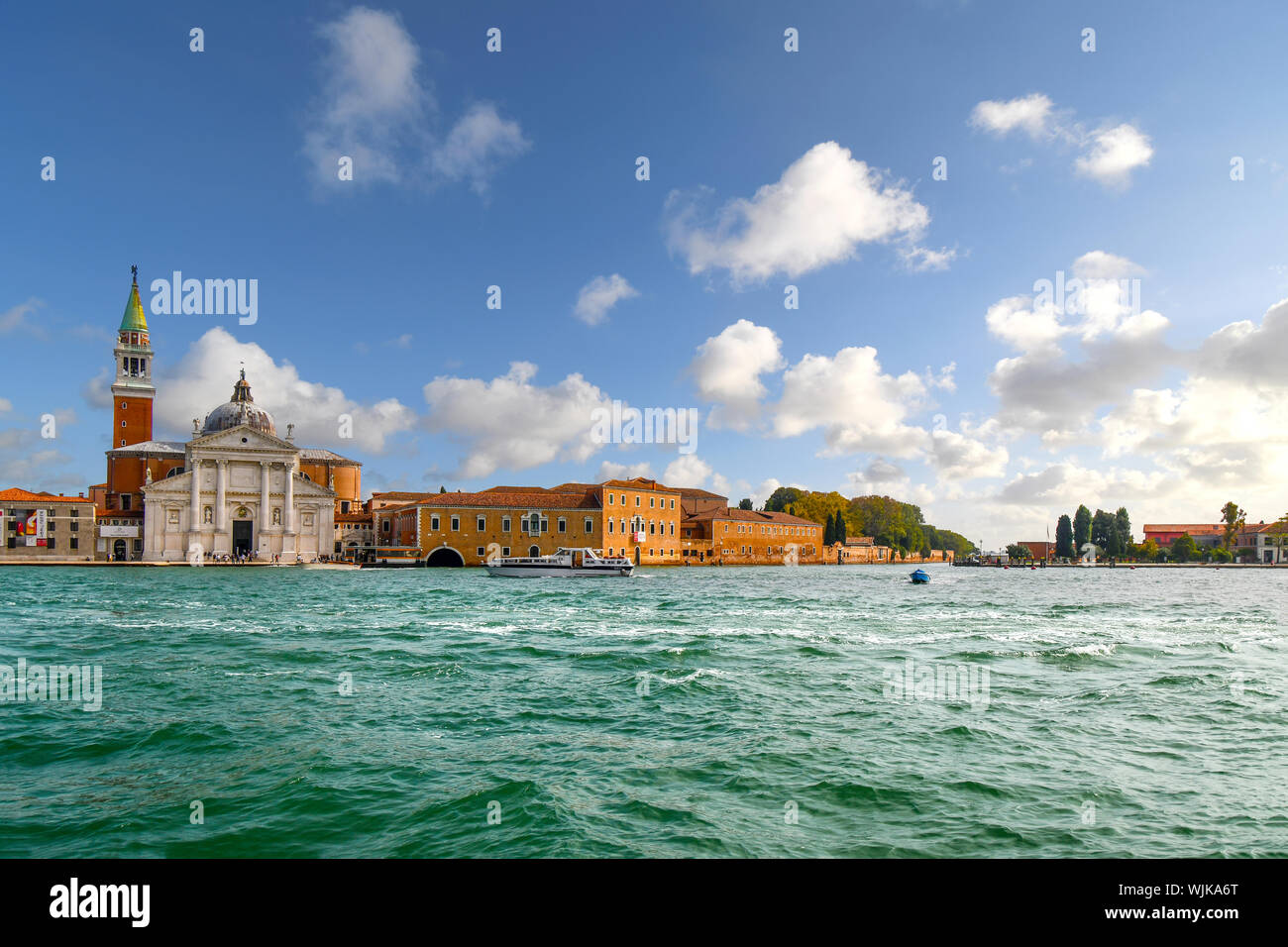 Un petit bateau passe en face de San Giorgio Maggiore, l'Église du xvie siècle et la tour de l'île de San Giorgio Maggiore, à Venise, Italie. Banque D'Images