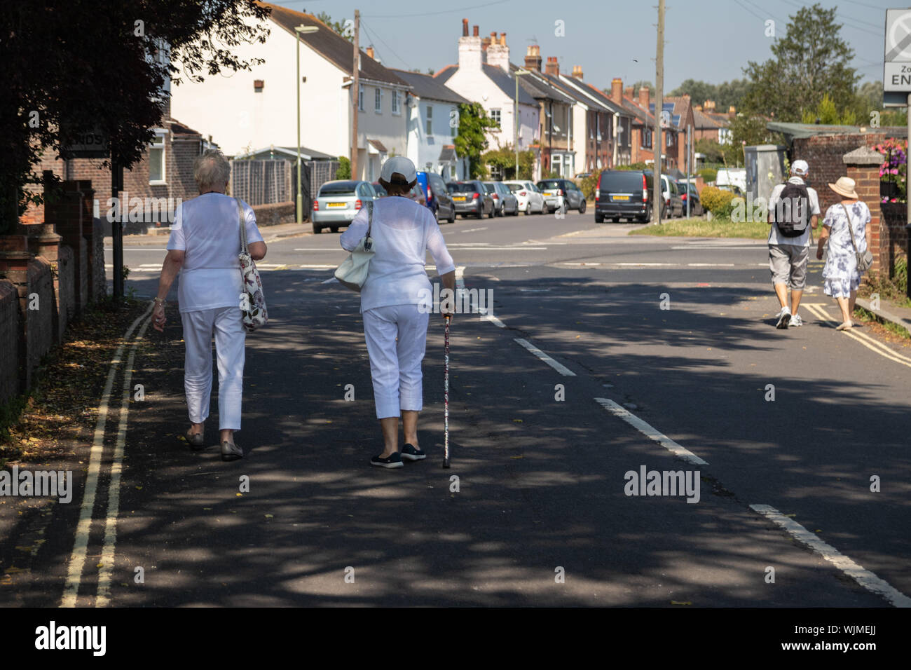 Deux femmes âgées marchant dans une rue, l'une des femmes est à l'aide d'un bâton de marche ou d'aide à la marche Banque D'Images