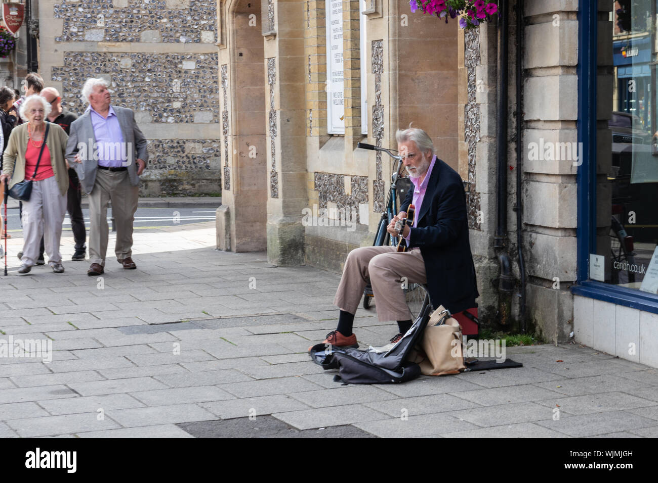 Winchester, Hampshire, UK a middle aged bien habillée busker rue jouant de la guitare Banque D'Images