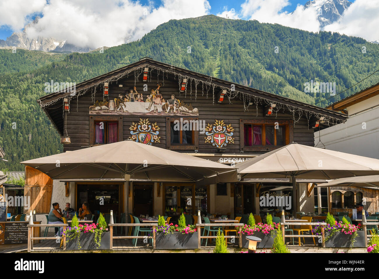 De l'extérieur d'un café avec terrasse dans un style alpin typique dans le centre de Chamonix-Mont-Blanc avec le massif du Mont Blanc en arrière-plan en été, France Banque D'Images