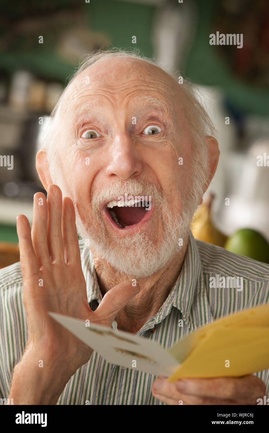 Senior man at home reading carte de souhaits Banque D'Images