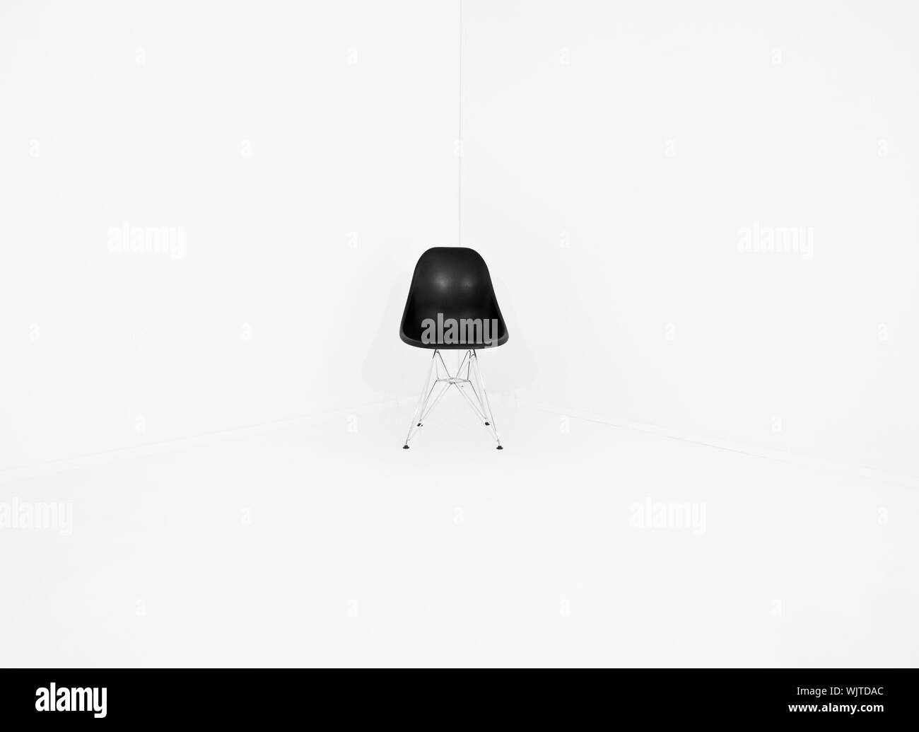 Chaise rétro solitaire dans un coin d'une salle blanche Banque D'Images