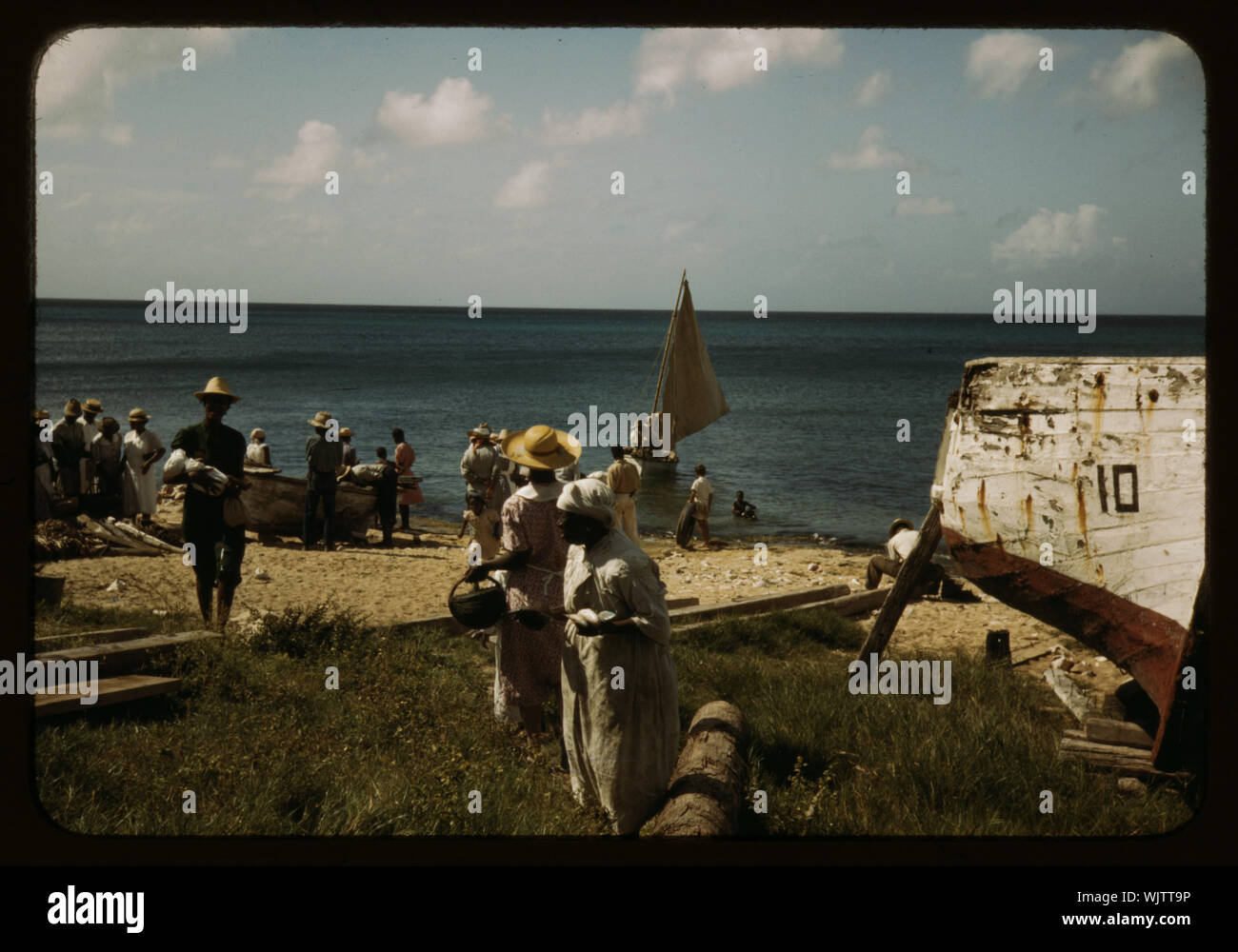 Les femmes au foyer au bord de la mer attendent les bateaux de pêche à venir à Frederiksted, Saint Croix, Îles Vierges Américaines Banque D'Images