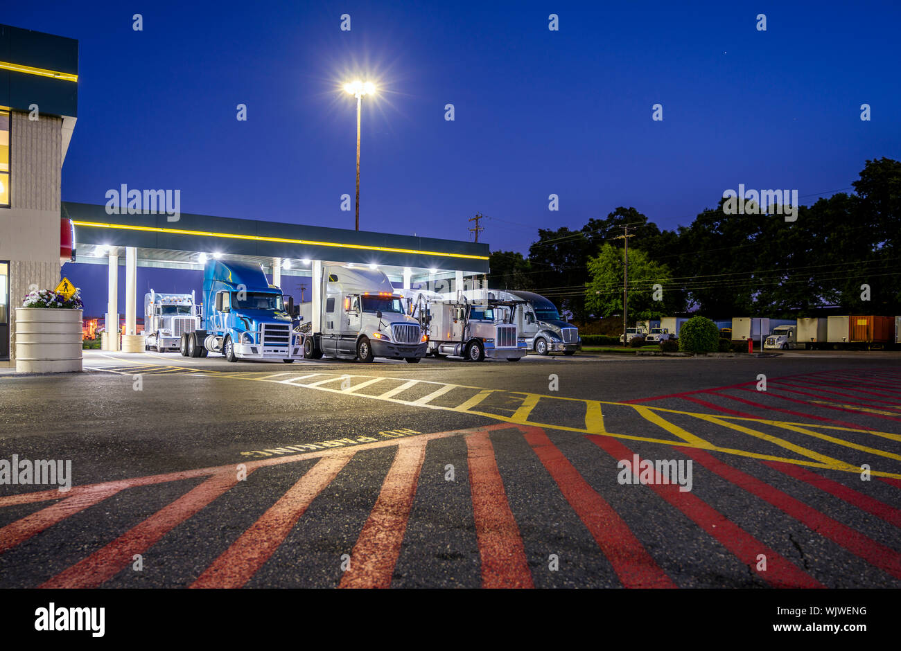 Faire différents modèles et les camions avec semi-remorques semi-remorques semi permanent sur l'arrêt de camion parking éclairé sous l'abri dans la nuit et se conformer Banque D'Images