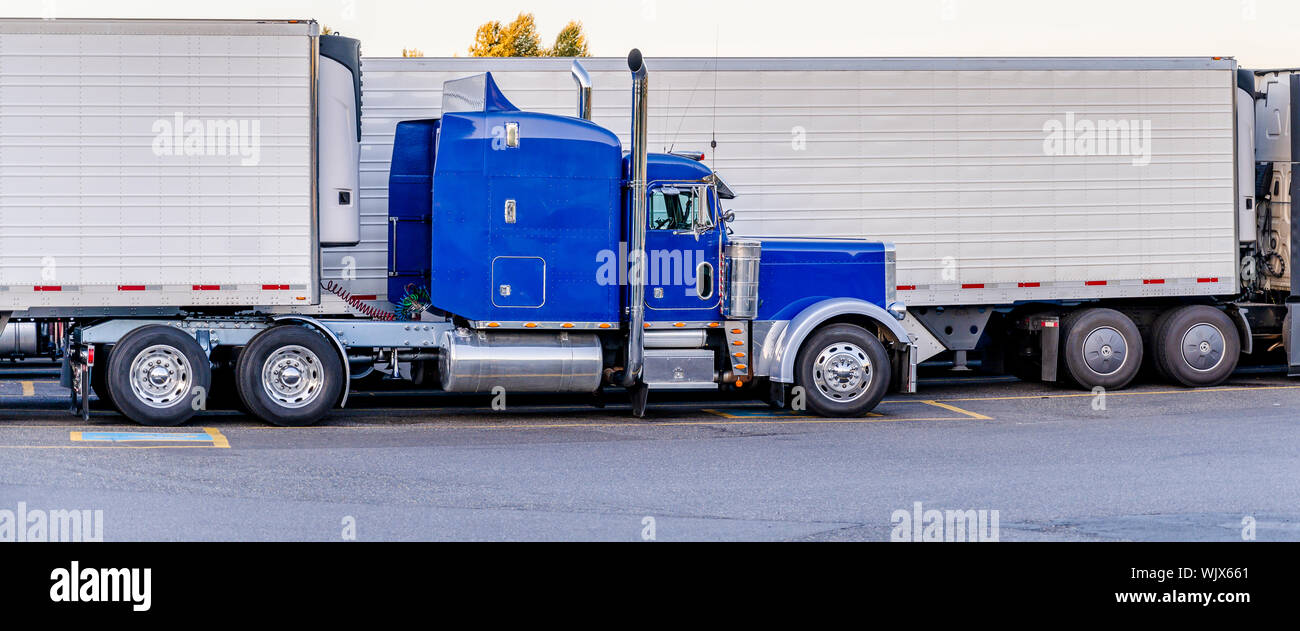 Big Rig classic American Idol de qualité industrielle bleu semi truck avec tuyaux de transport de fret en chrome réfrigérateur semi-remorque debout sur le chariot Banque D'Images