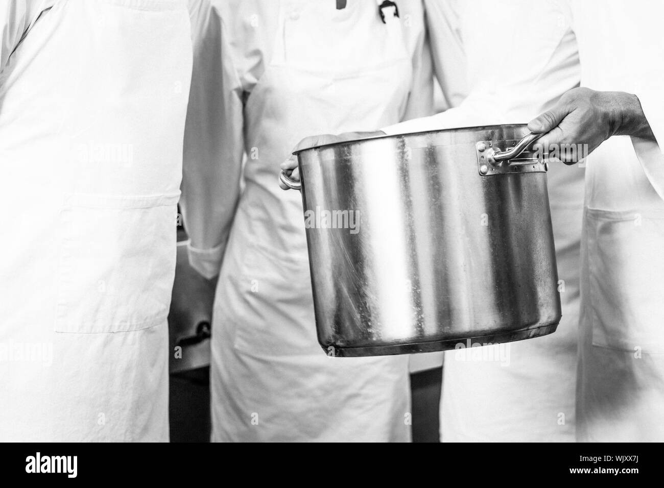 Chef holding grand pot dans une cuisine commerciale Banque D'Images