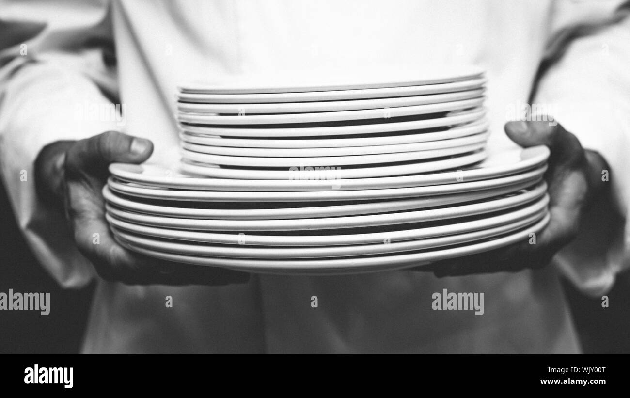 Chef holding pile d'assiettes dans une cuisine commerciale Banque D'Images