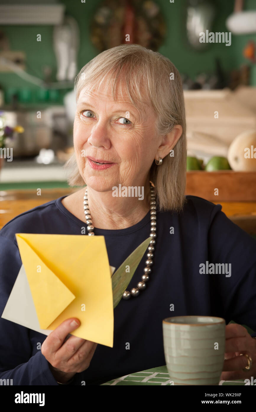 Senior woman at home reading carte de souhaits Banque D'Images
