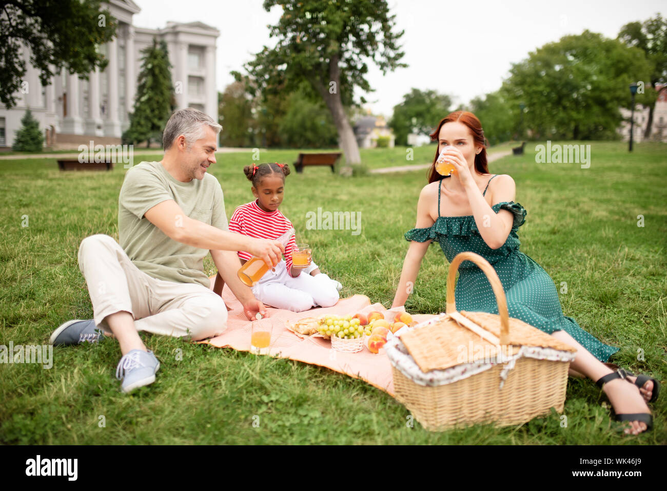 Fille joyeuse sensation tout en ayant des parents adoptifs avec pique-nique Banque D'Images