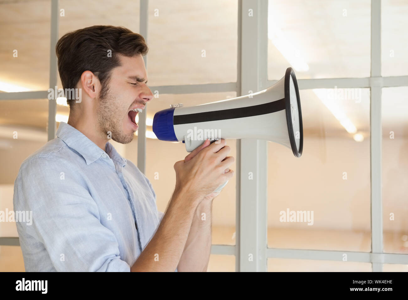 Businessman shouting par mégaphone dans son bureau Banque D'Images