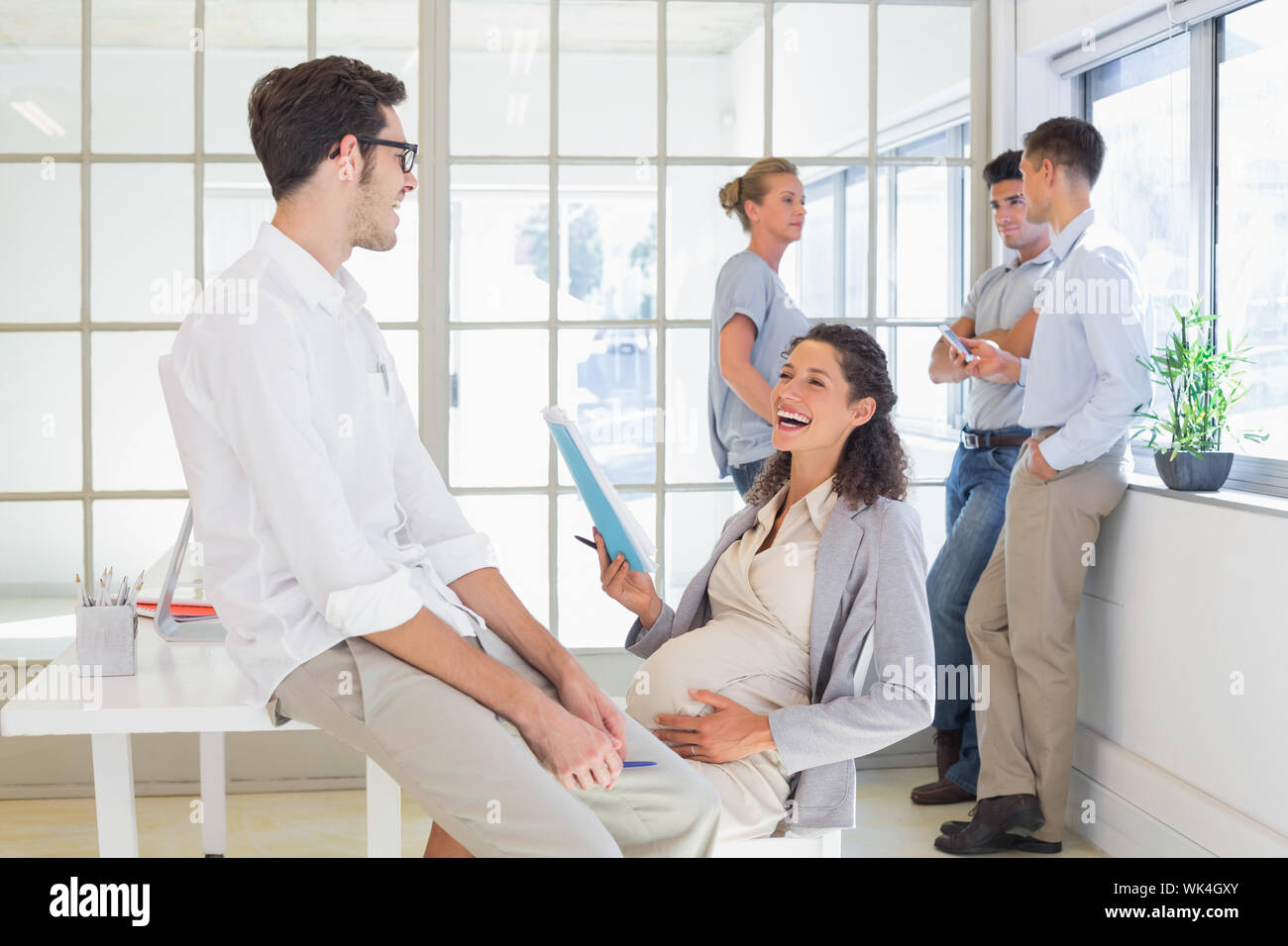 Businesswoman laughing enceinte avec un collègue au bureau Banque D'Images