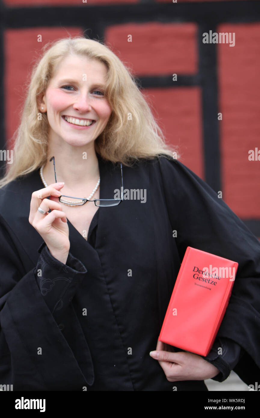 Friendly smiling étudiant en droit ou d'un avocat avec red law book sous le bras et des verres dans la main Banque D'Images