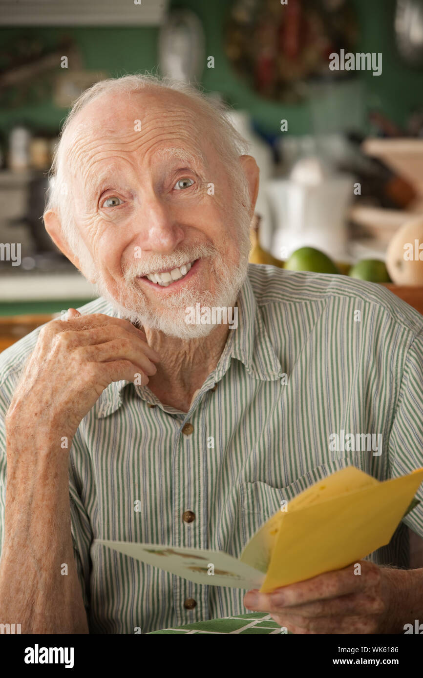 Senior man at home reading carte de souhaits Banque D'Images
