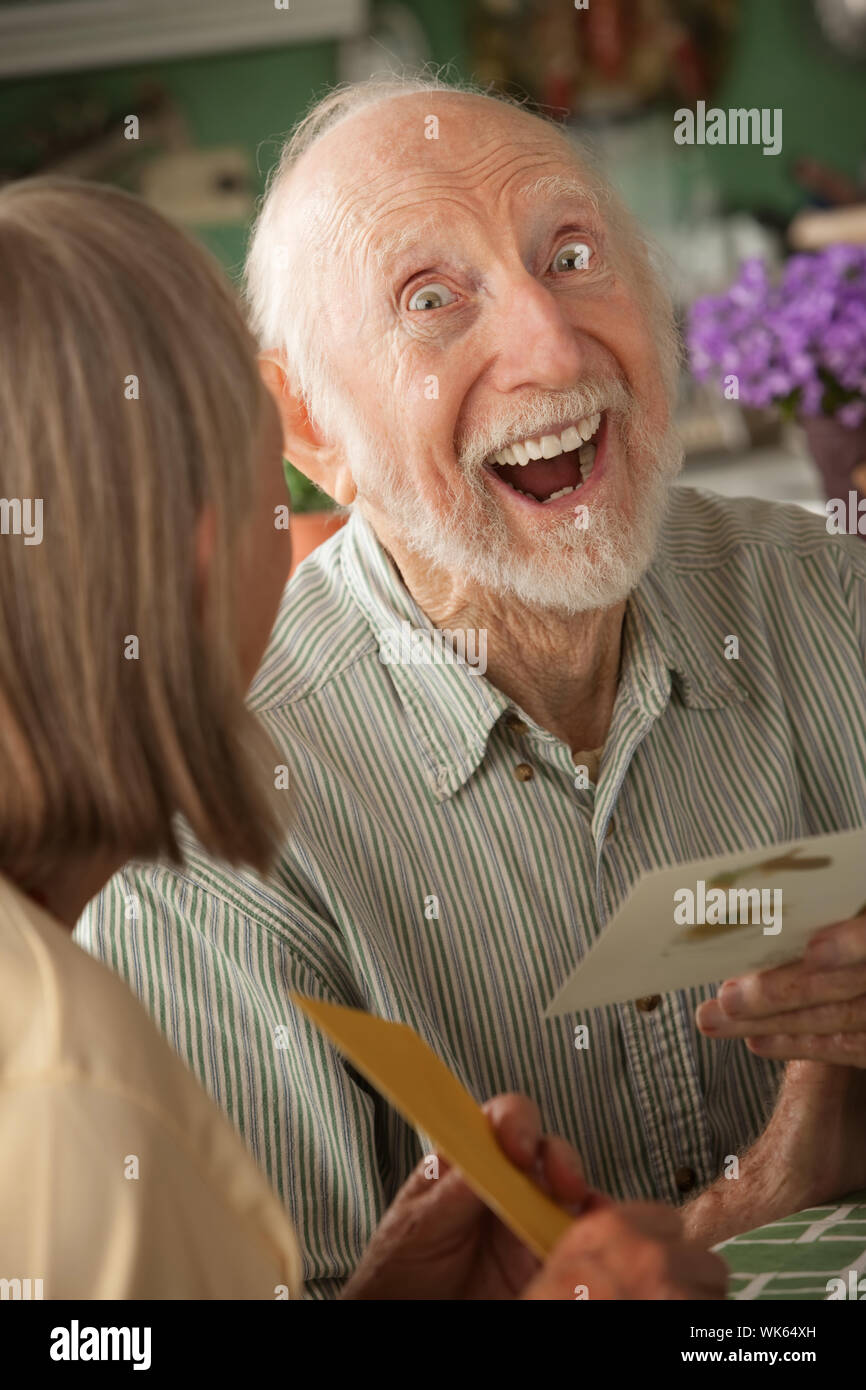 Senior man at home reading carte de souhaits avec femme Banque D'Images