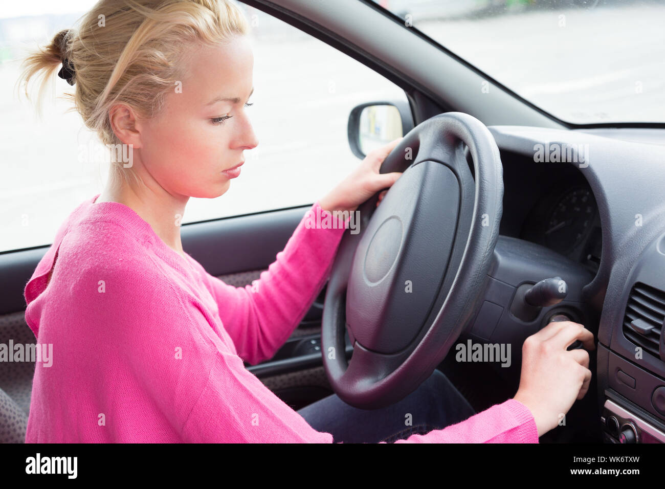 Belle femme vêtue à la légère voiture chauffeur de démarrer le moteur. Banque D'Images