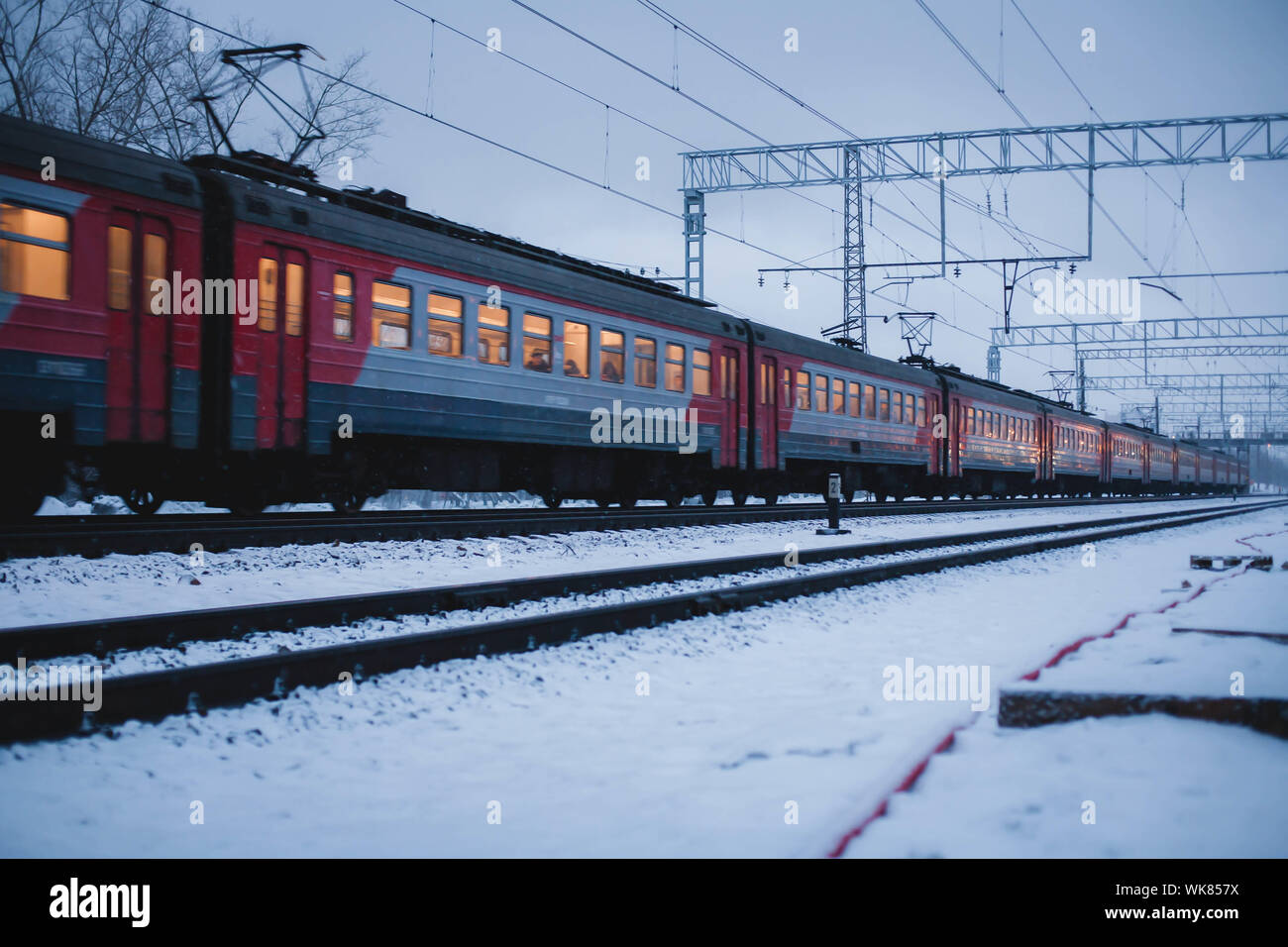 Passage de trains de passagers à grande vitesse dans la neige. Les lignes de chemin de fer/piste visible dans l'avant-plan avec la neige soulevée par le train. Banque D'Images