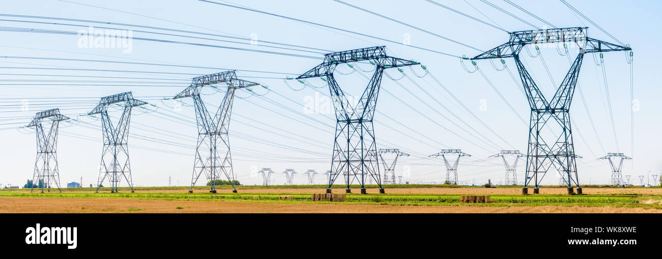 Vue panoramique sur une rangée de pylônes électriques dans la campagne française avec des dizaines d'autres pylônes au loin sous un ciel bleu clair. Banque D'Images