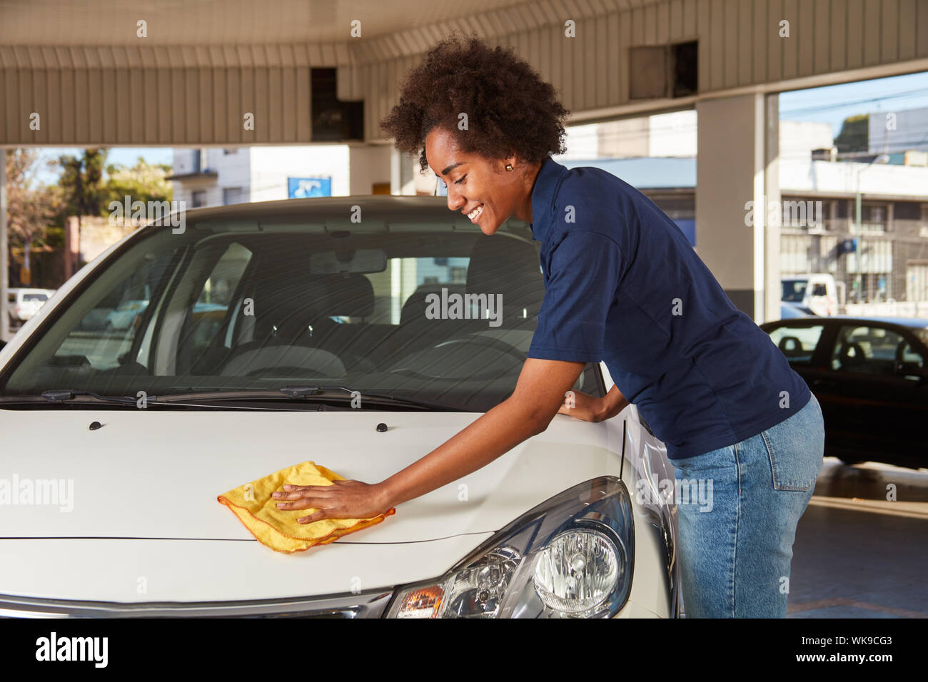 Femme africaine comme un mécanicien stagiaire, chiffon de polissage en voiture chez le concessionnaire Banque D'Images