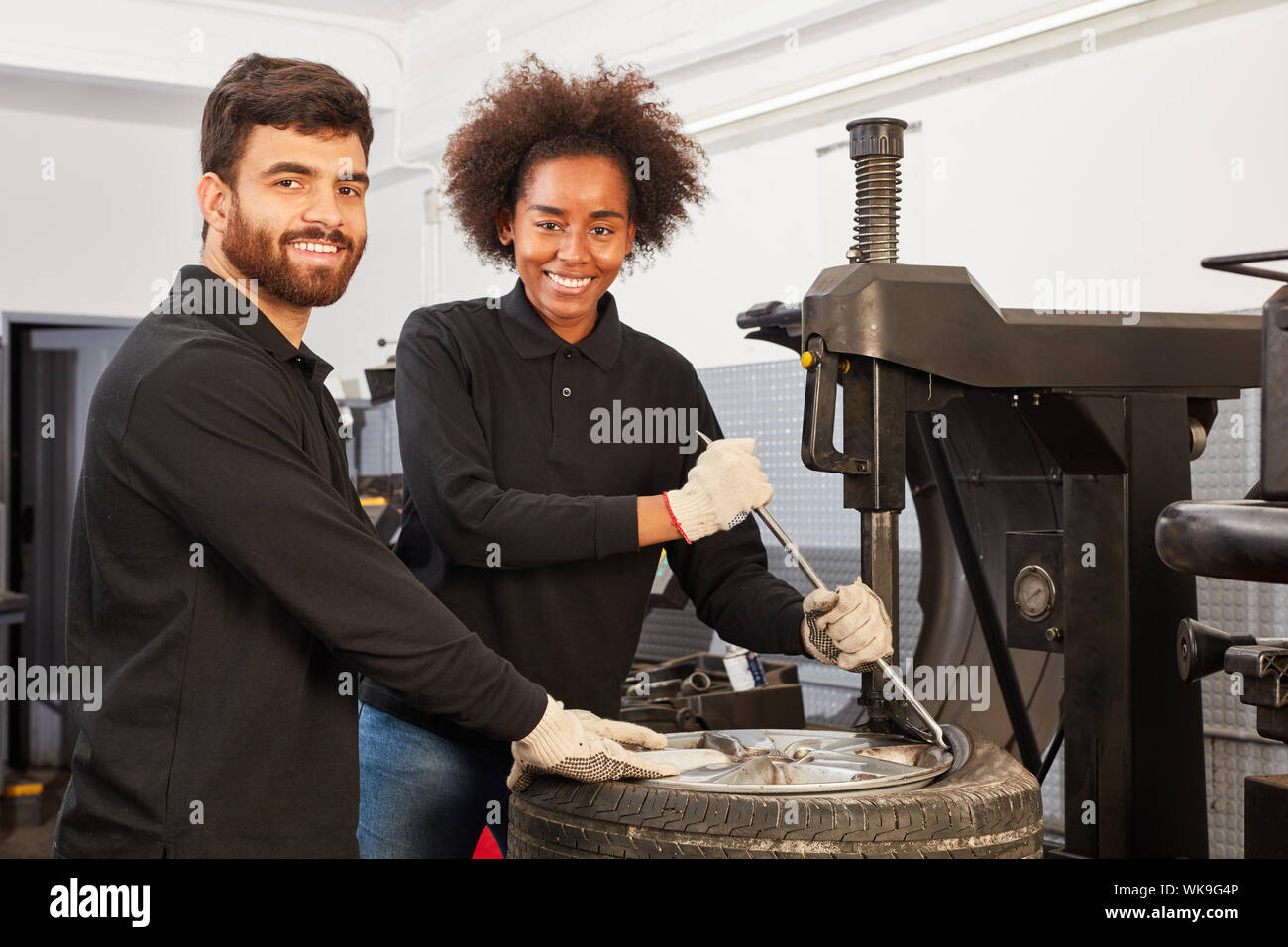 Les jeunes de l'équipe mécatronique multiculturelle avec changeur de pneus au stagiaire Banque D'Images