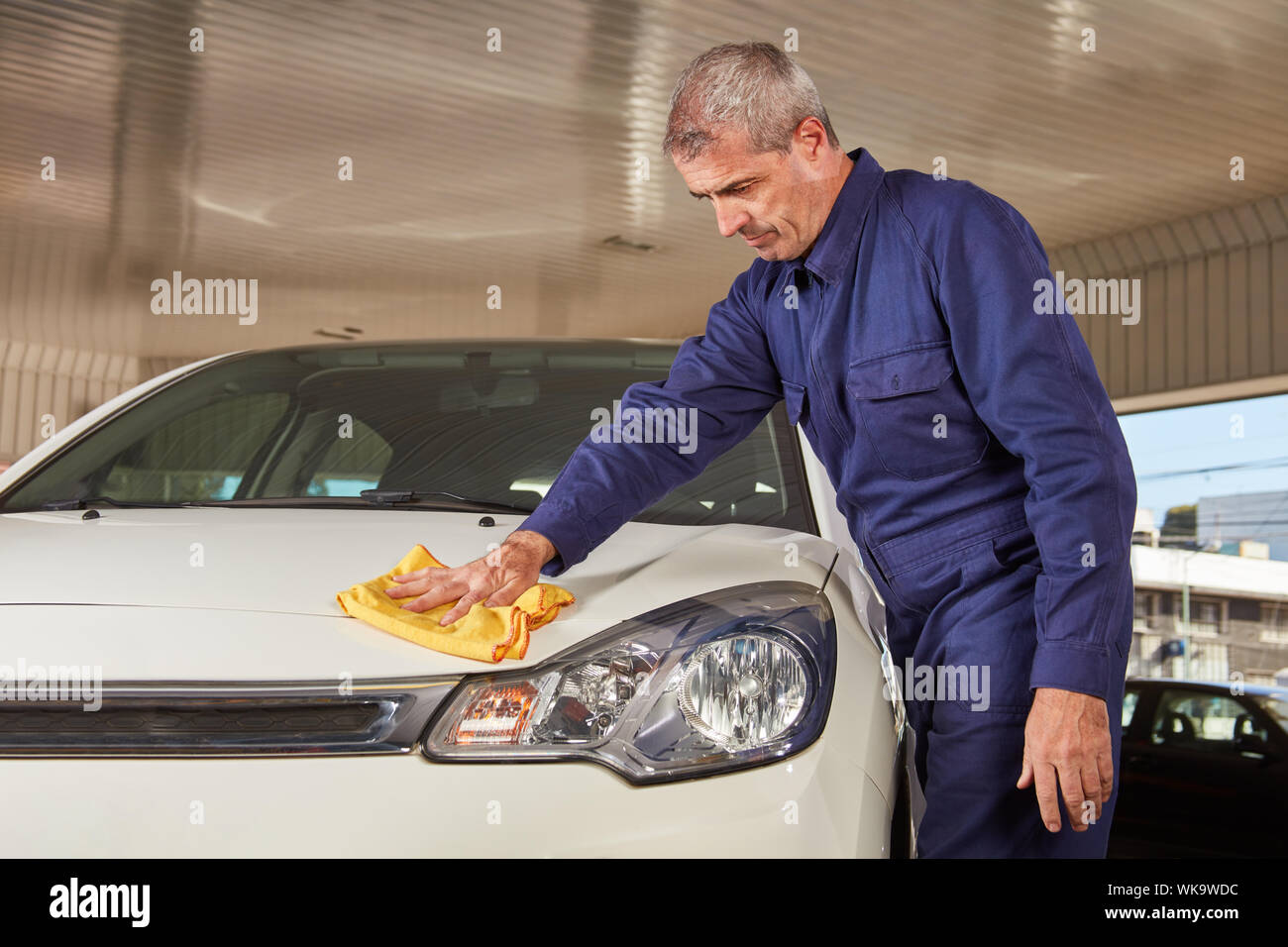Mécanicien automobile avec rag a le soin de la peinture après le lavage de voiture à l'atelier Banque D'Images