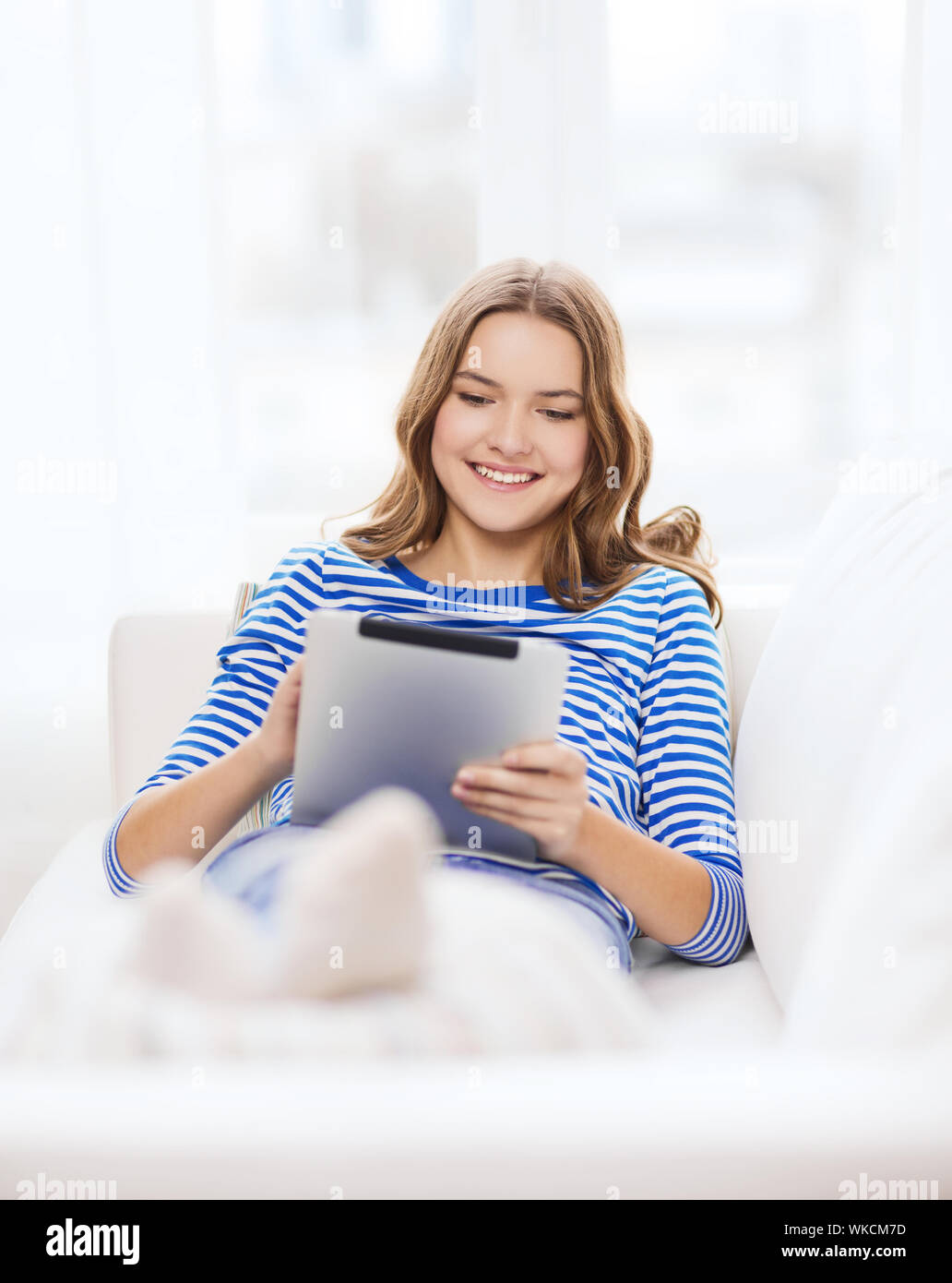 Accueil, de la technologie et de l'internet - concept teenge smiling girl couché sur la table avec tablette PC ordinateur à domicile Banque D'Images