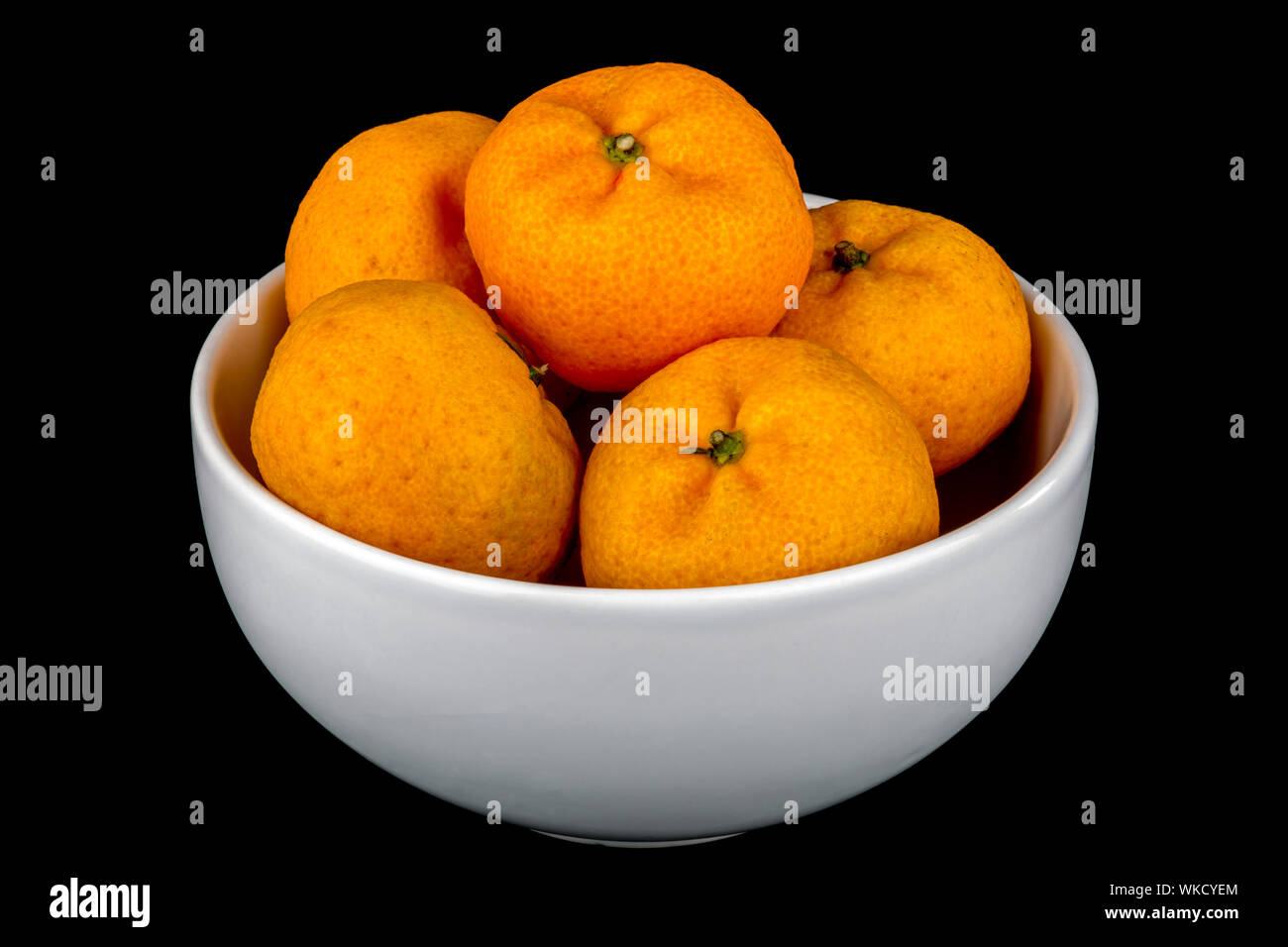 Petites mandarines dans Bol en céramique blanche sur fond noir Banque D'Images