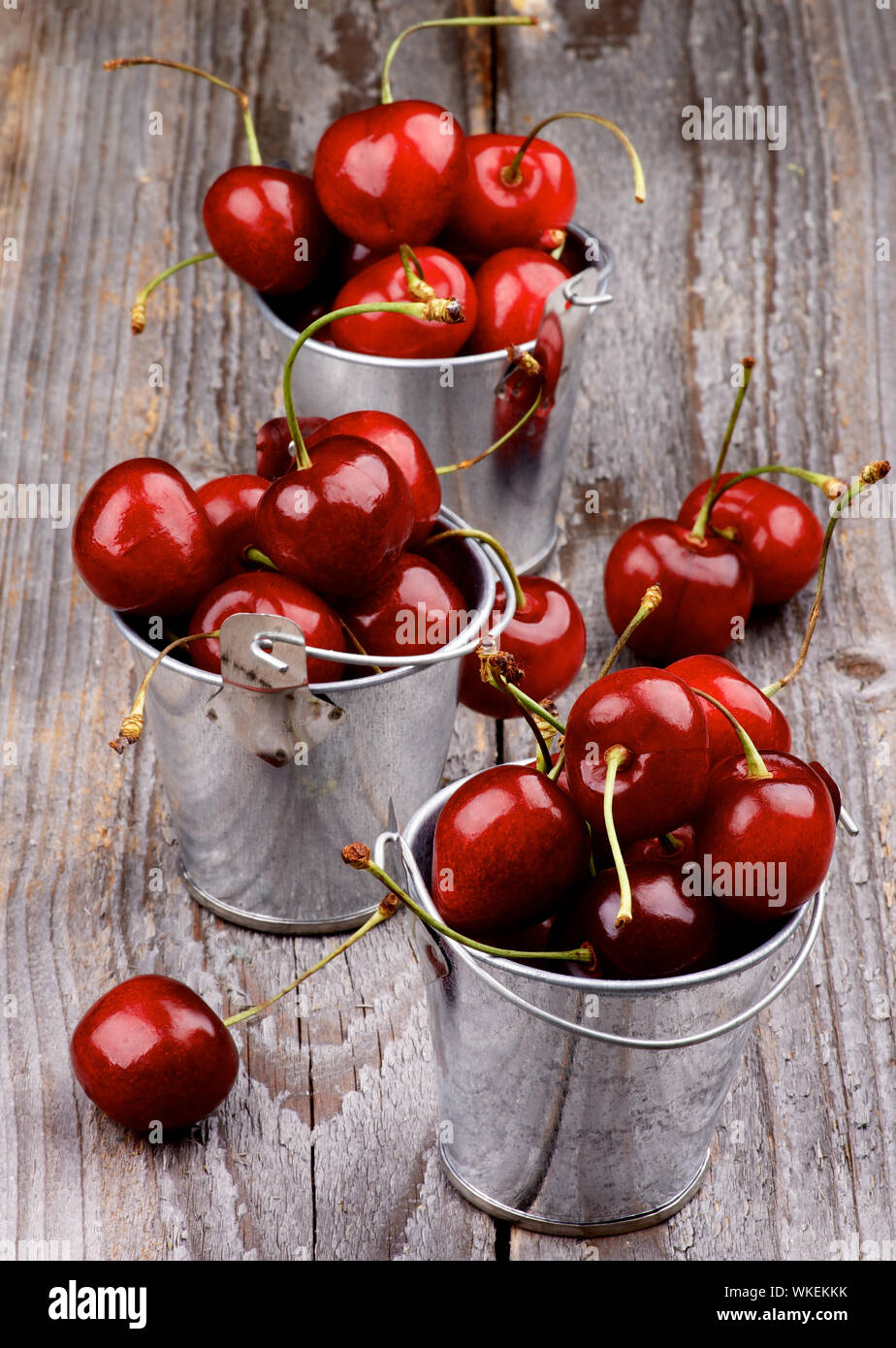 Les cerises mûres dans trois seaux en étain isolé sur fond de bois rustique Banque D'Images