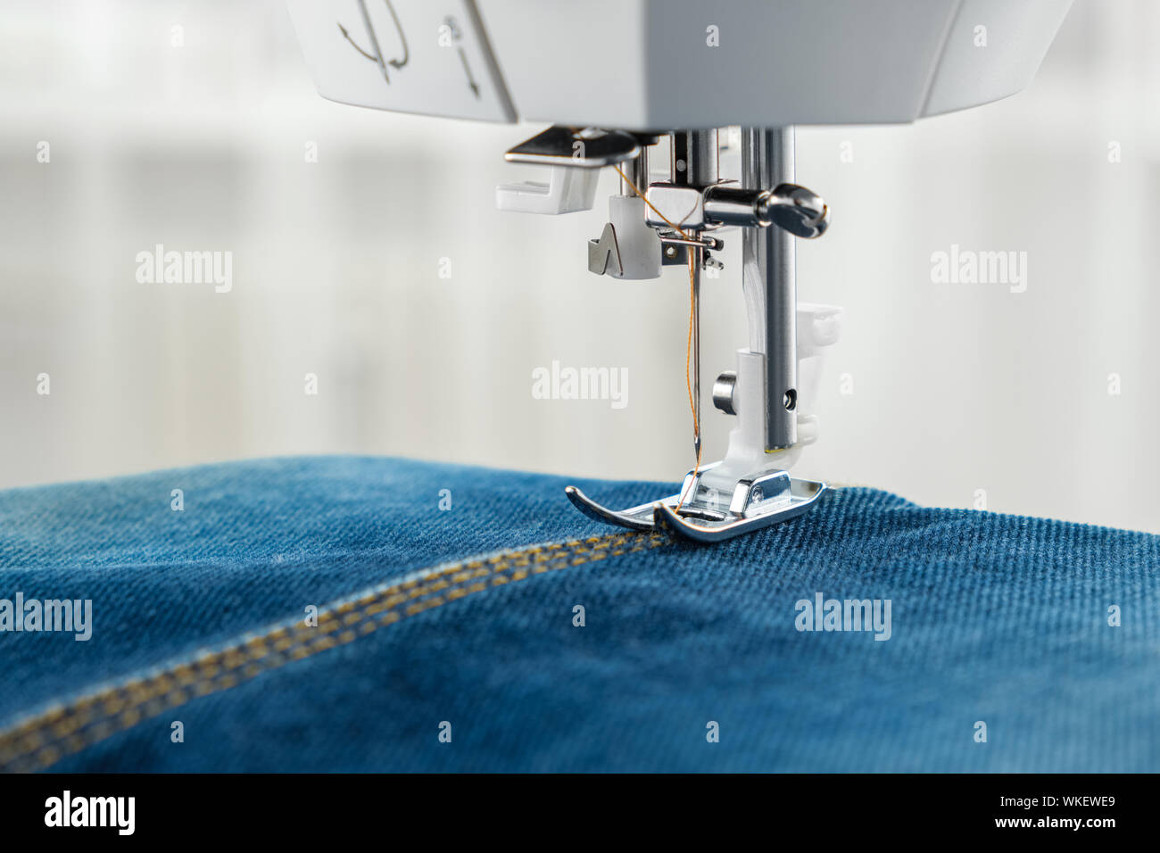 Jeans couture avec machine à coudre. Close up de l'aiguille de machine à coudre sur le tissu denim couture. Banque D'Images