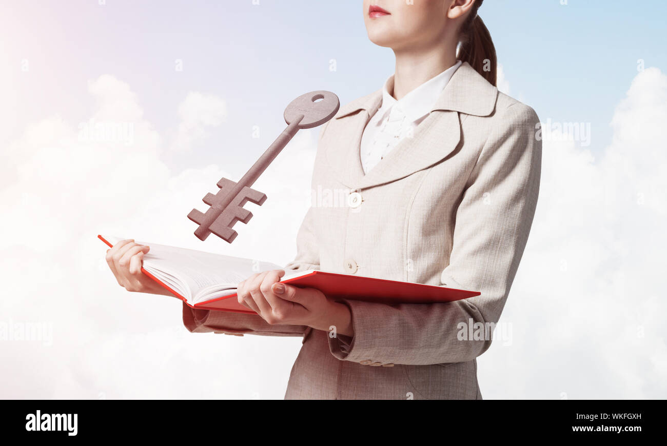 Femme montrant grande clé de métal au-dessus du livre ouvert. Agence immobilière la publicité. Vente et location de biens immobiliers commerciaux et privés. Consultant élégant Banque D'Images